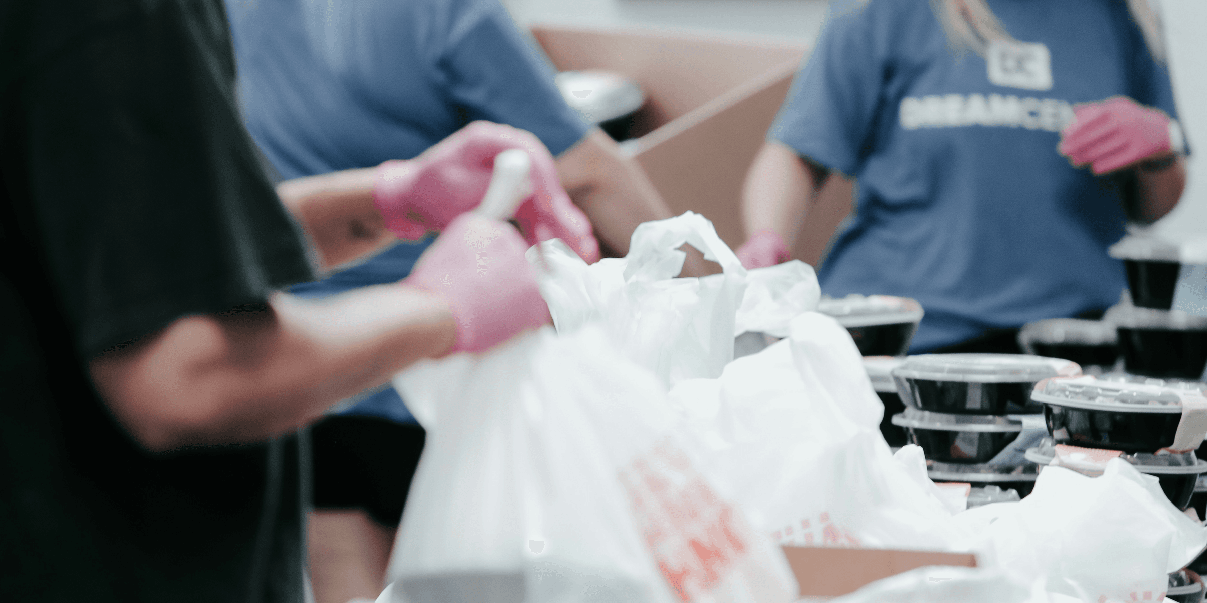 person in blue crew neck t-shirt holding white plastic bag.