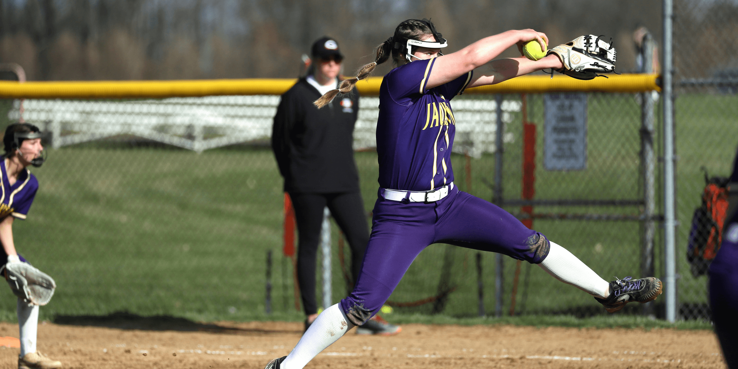a softball player throwing a ball on a field.