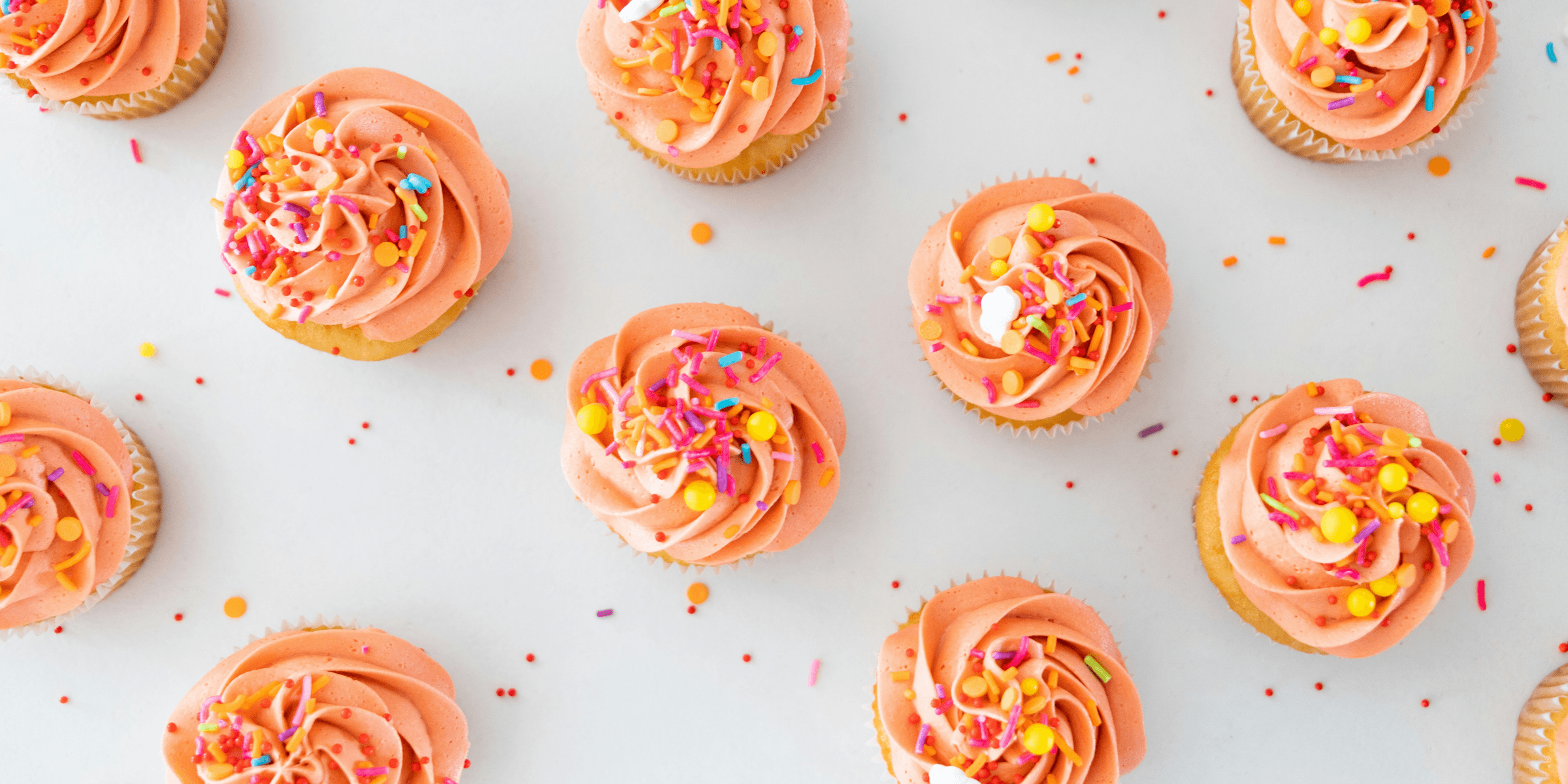 a table topped with lots of cupcakes covered in frosting.