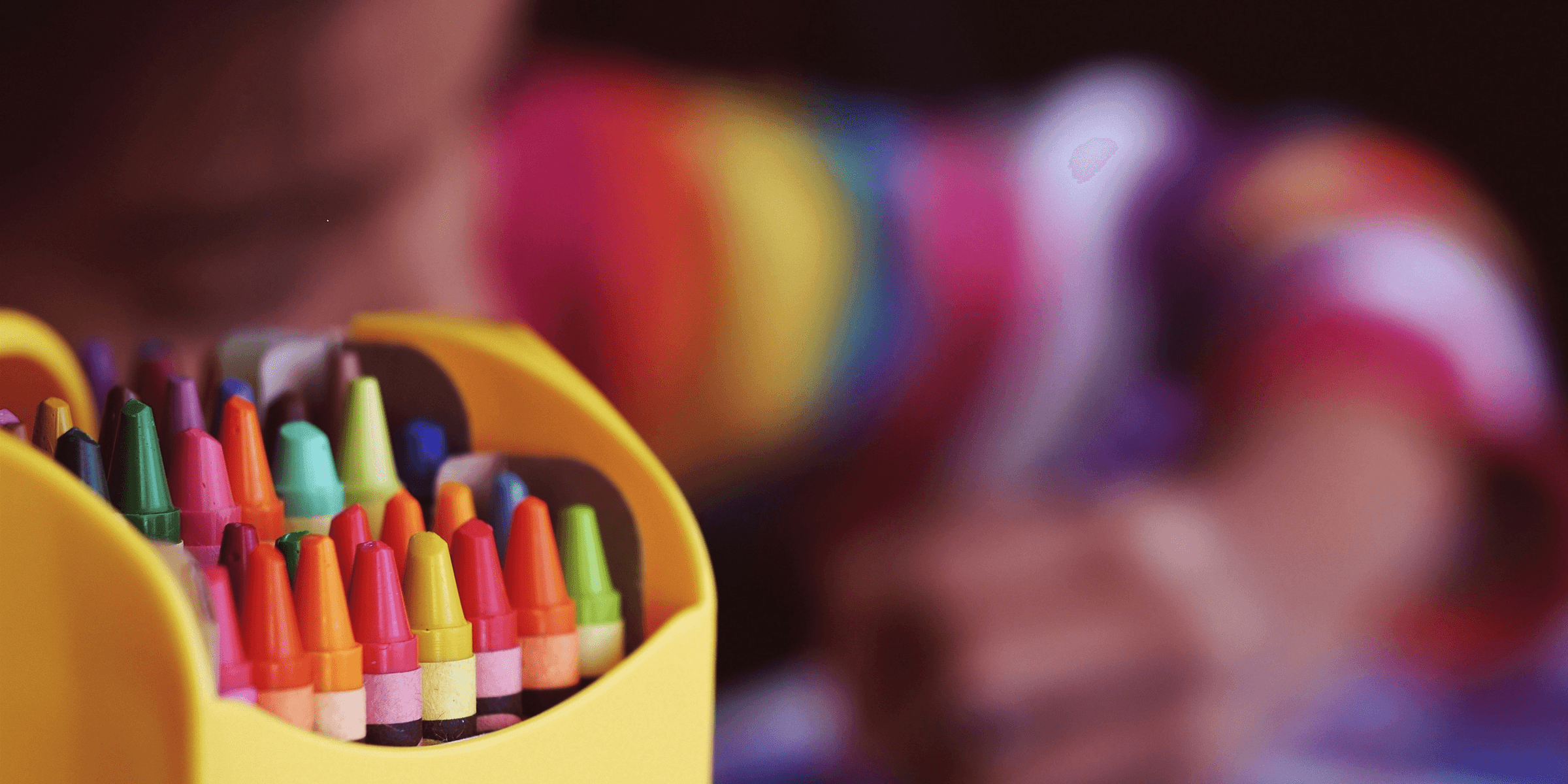 selective focal photo of crayons in yellow box.