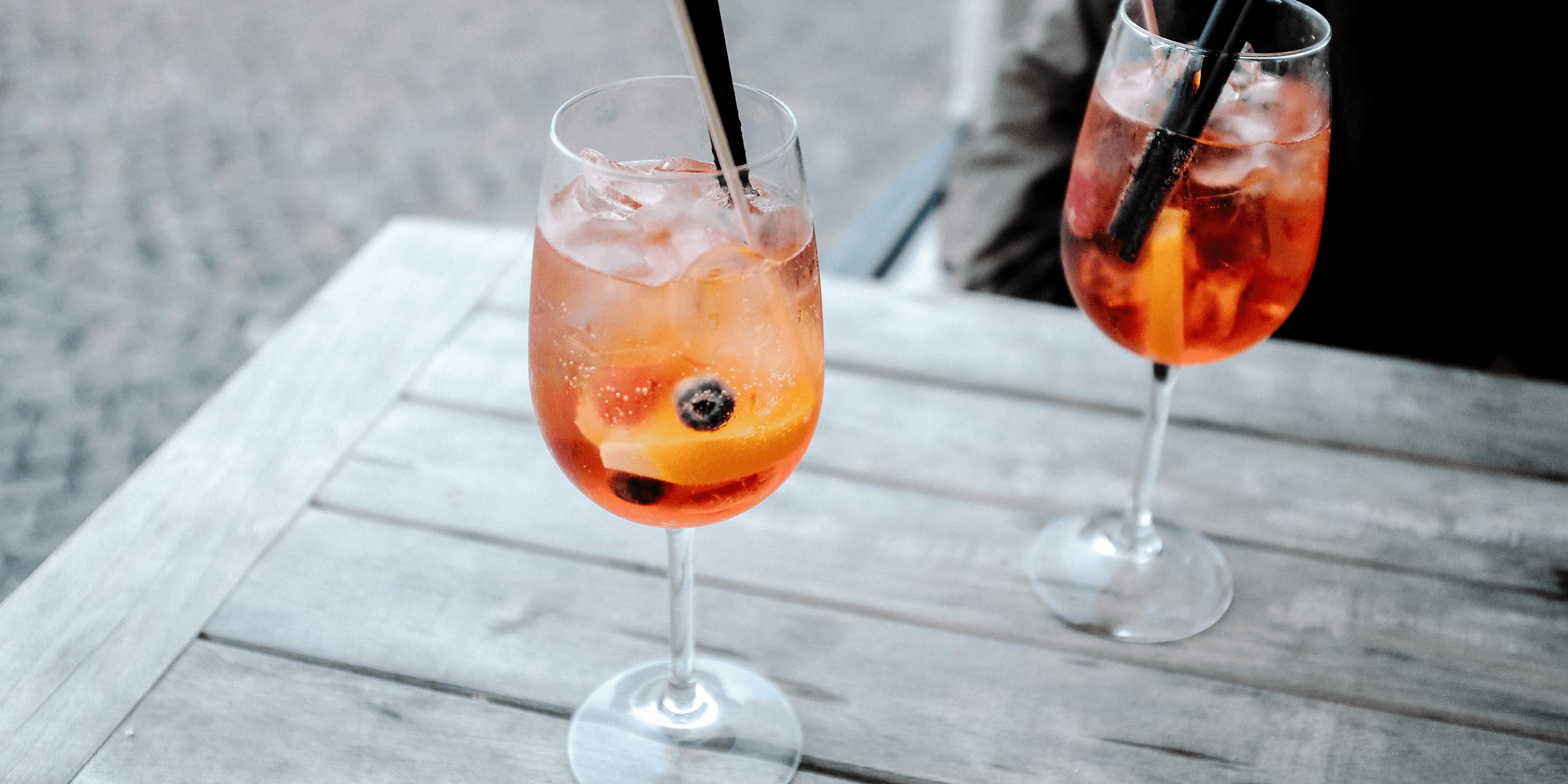 two clear wine glasses on brown wooden table.
