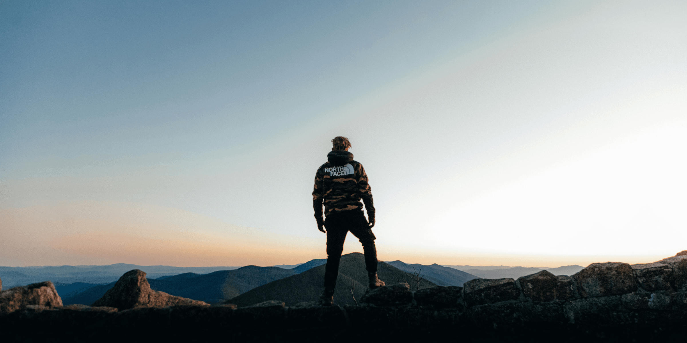 man in black jacket standing on top of mountain during daytime