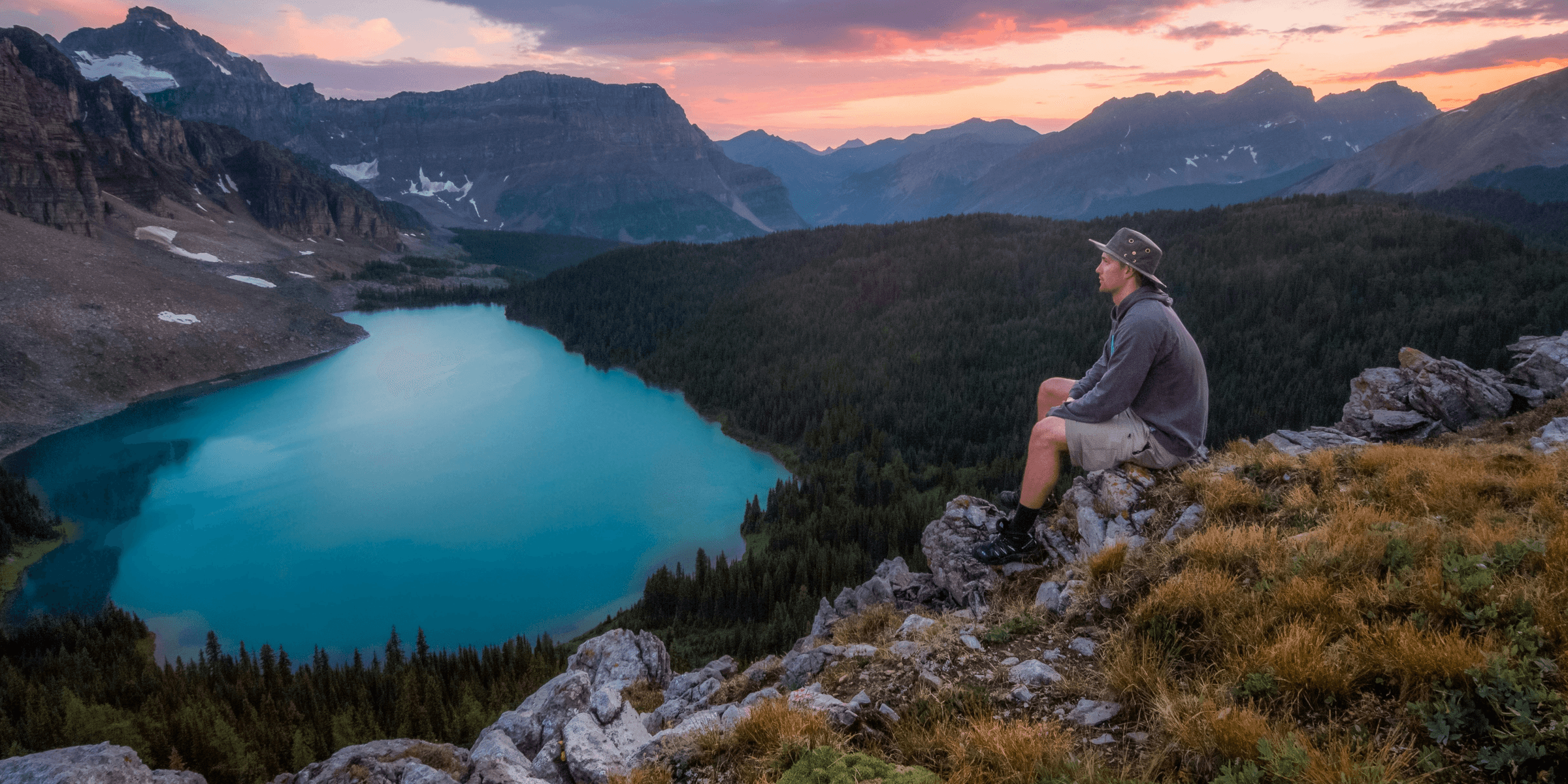 man looking on mountain sitting on rock.