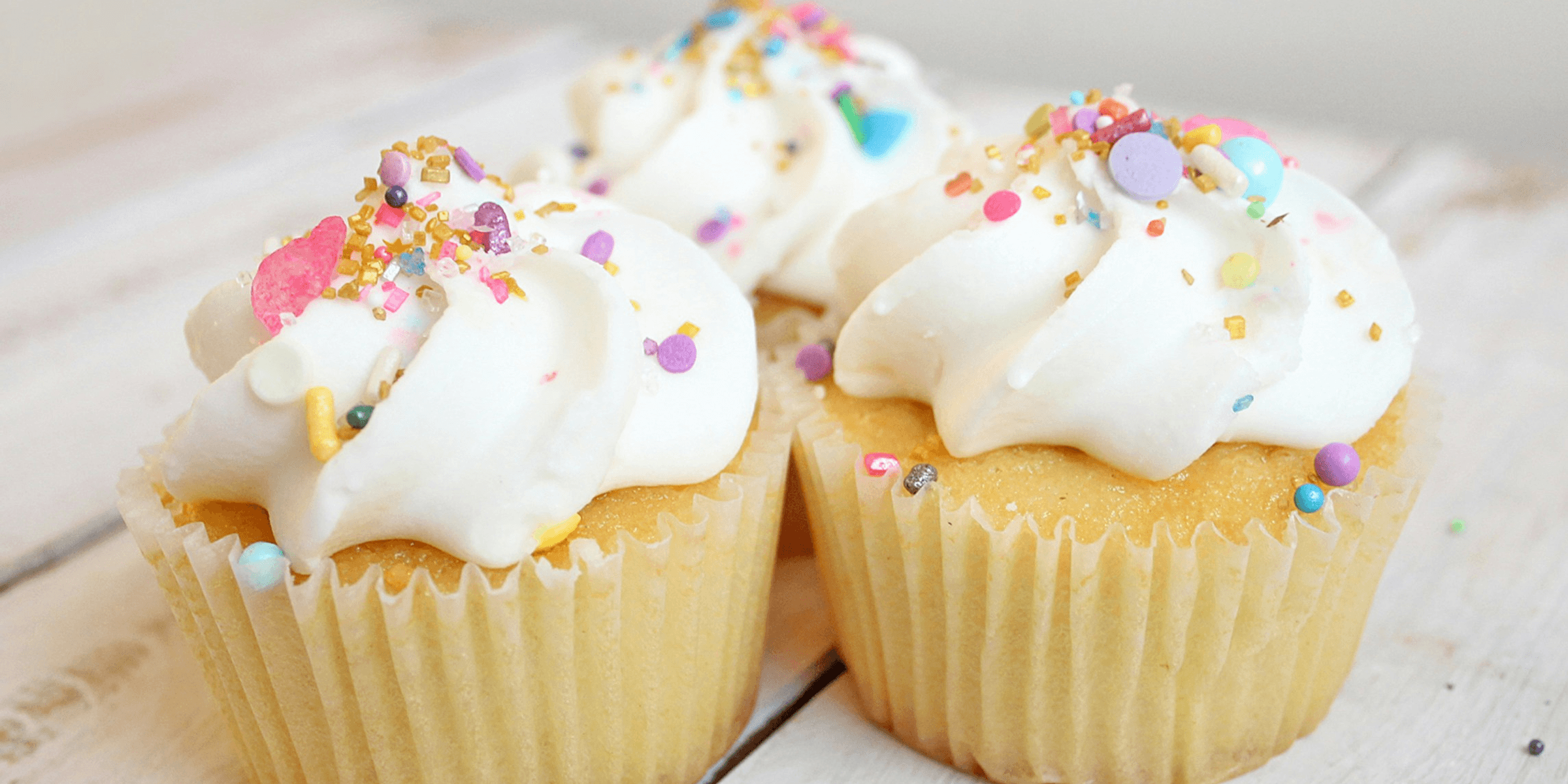 three cupcakes on white wood.
