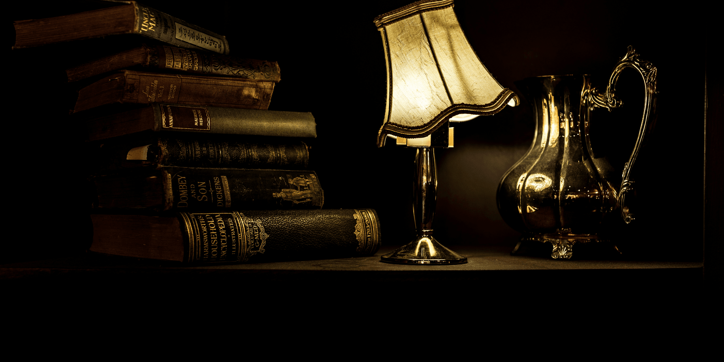 turned on desk lamp beside pile of books.