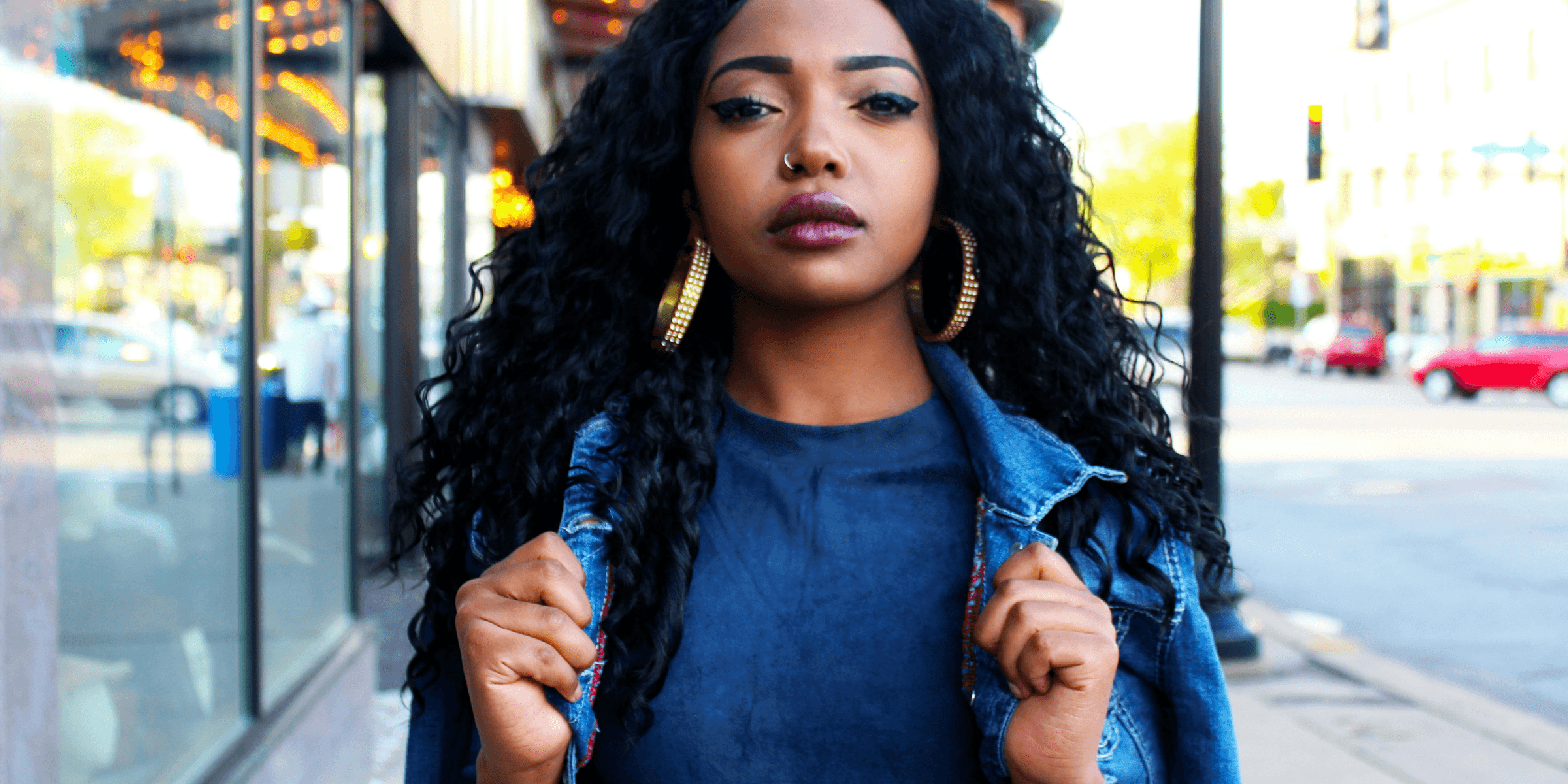 women holding denim jacket near glass window.