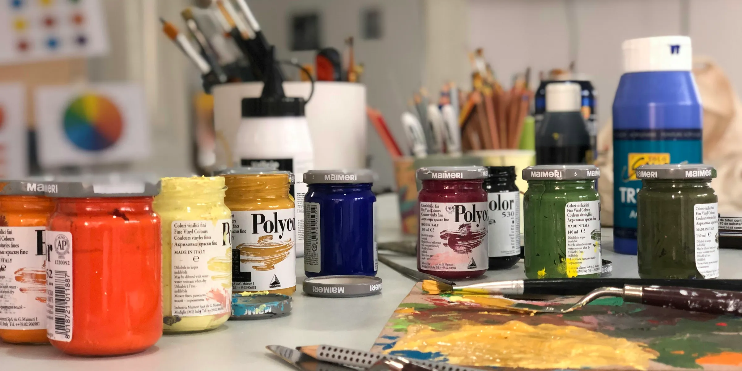 A white table topped with lots of paint and brushes