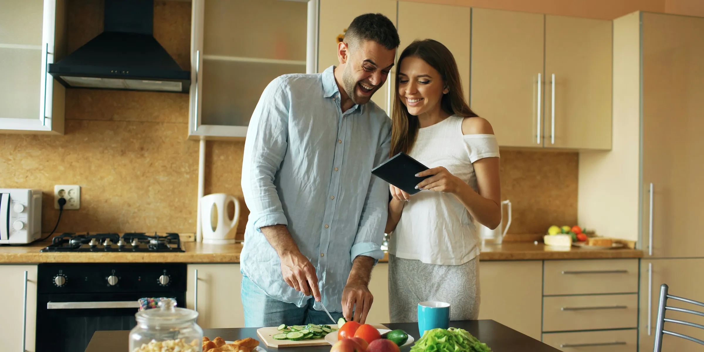 Couple smiling while preparing food in kitchen