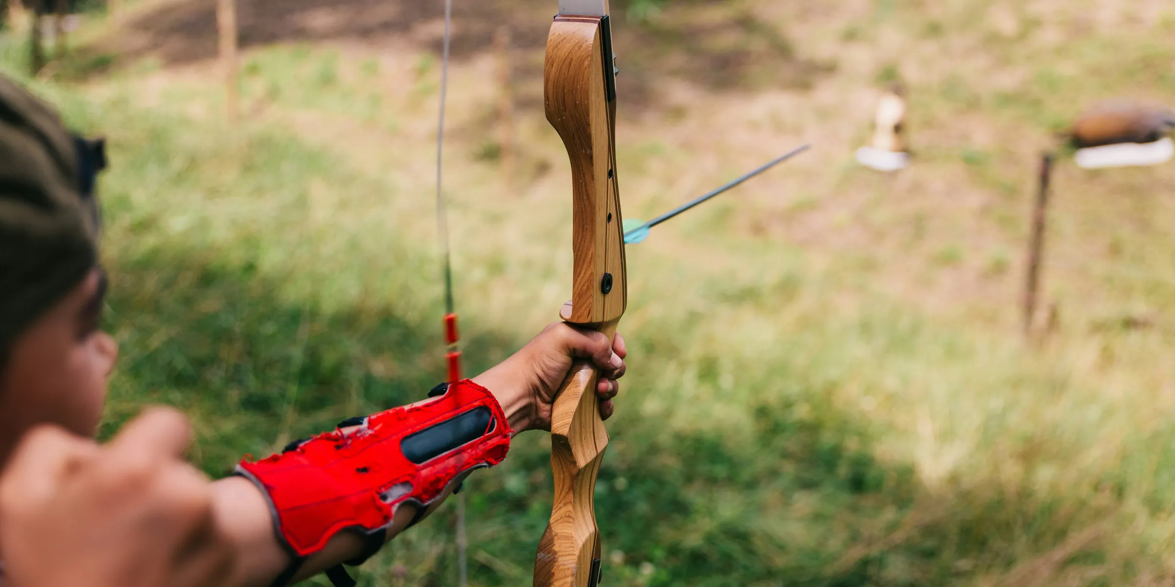 person using bow aiming person from afar during daytime