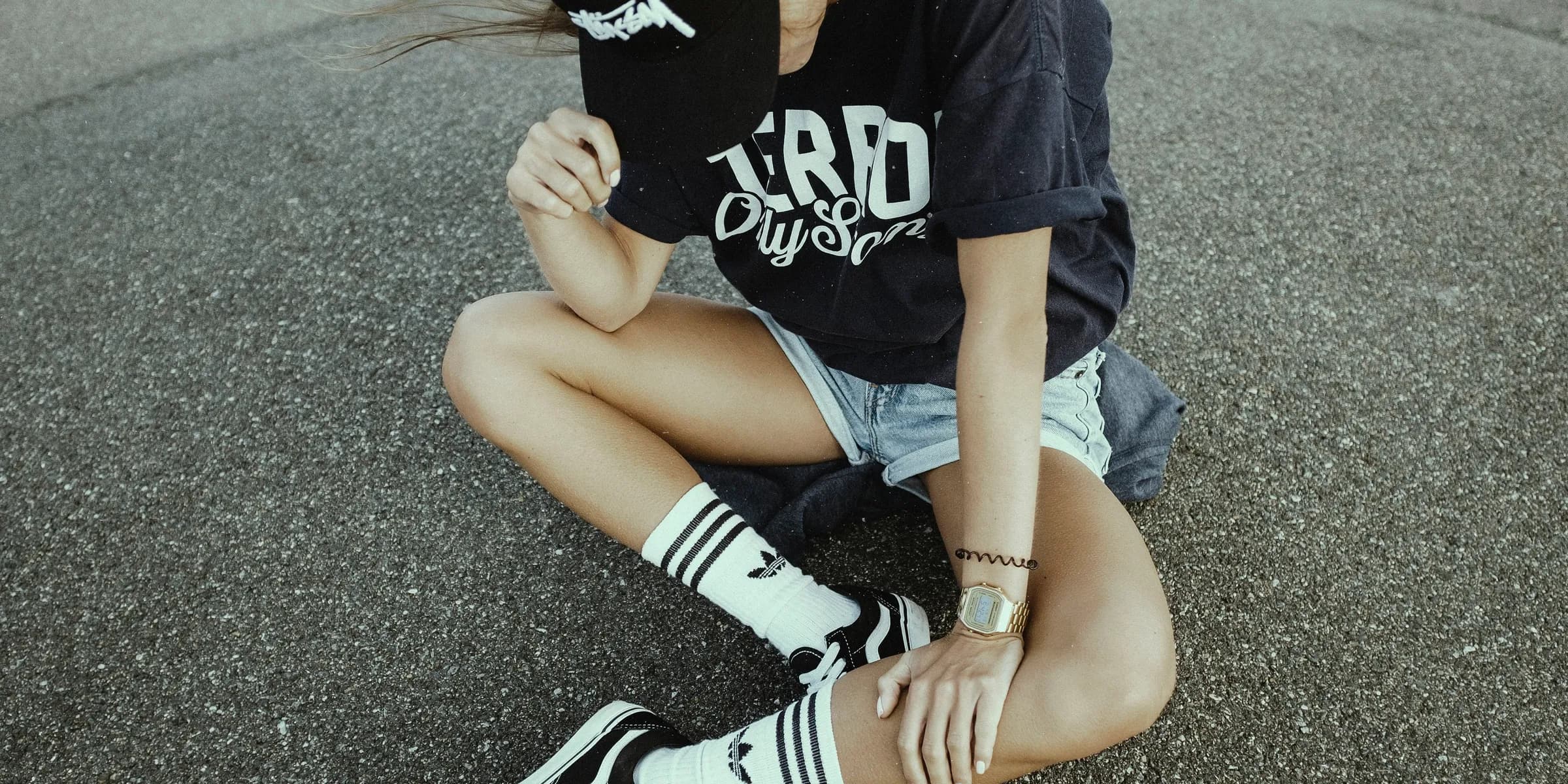 woman wearing black and white crew-neck shirt and gray shorts on gray concrete ground
