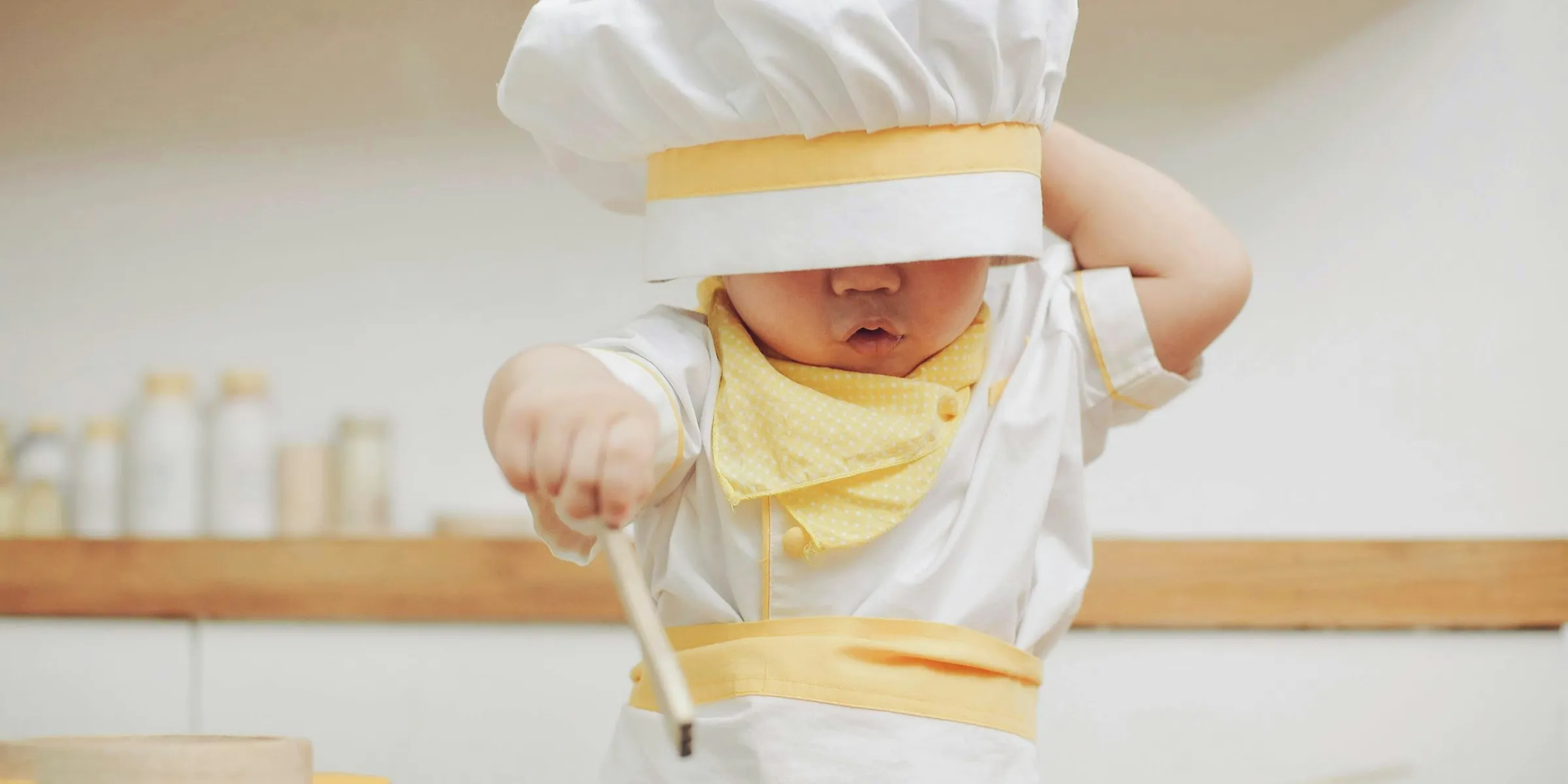 a young child wearing a chef's hat and holding a spoon