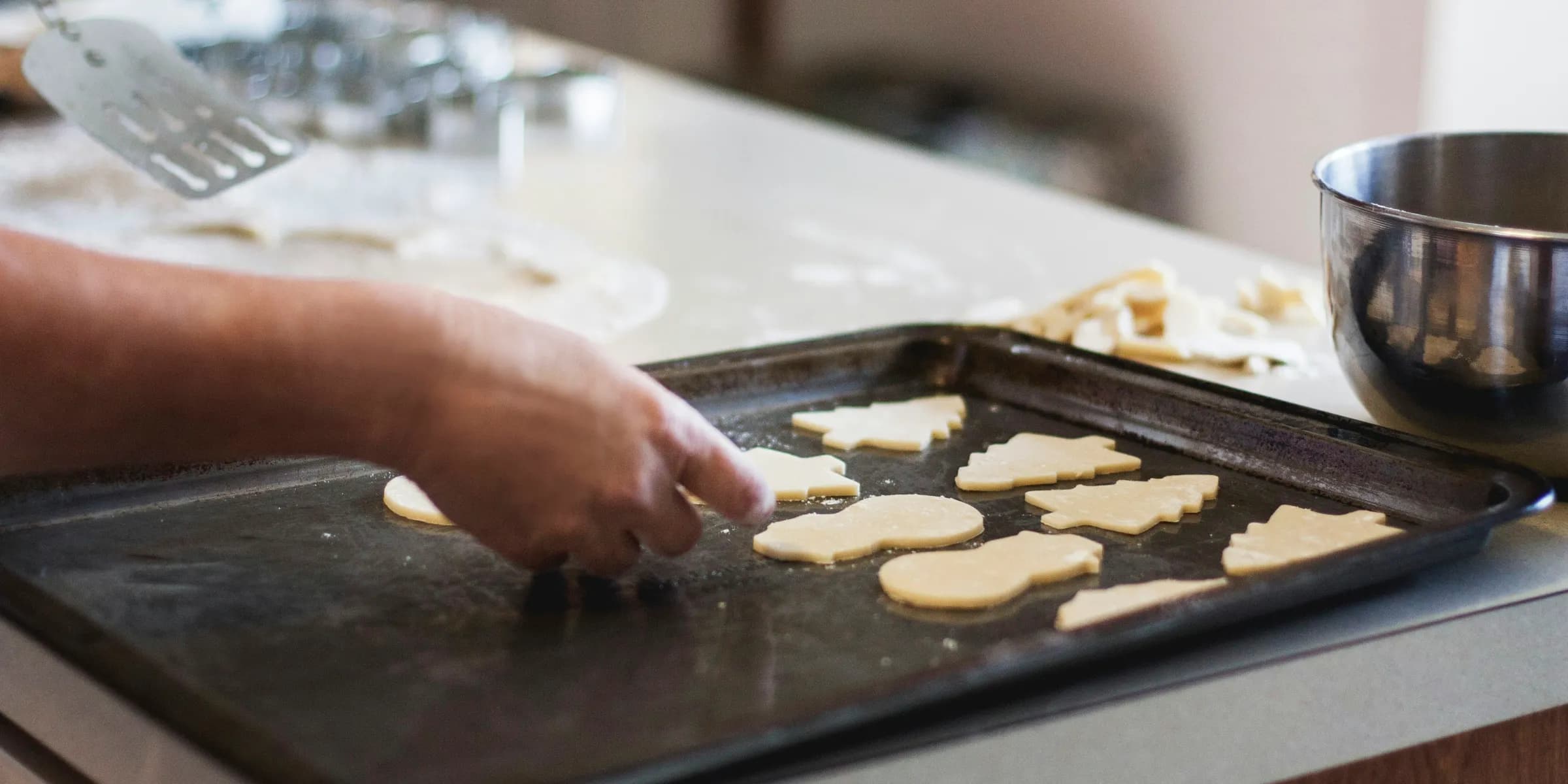 person lining assorted-shaped cookies on baking sheet inside kitchen