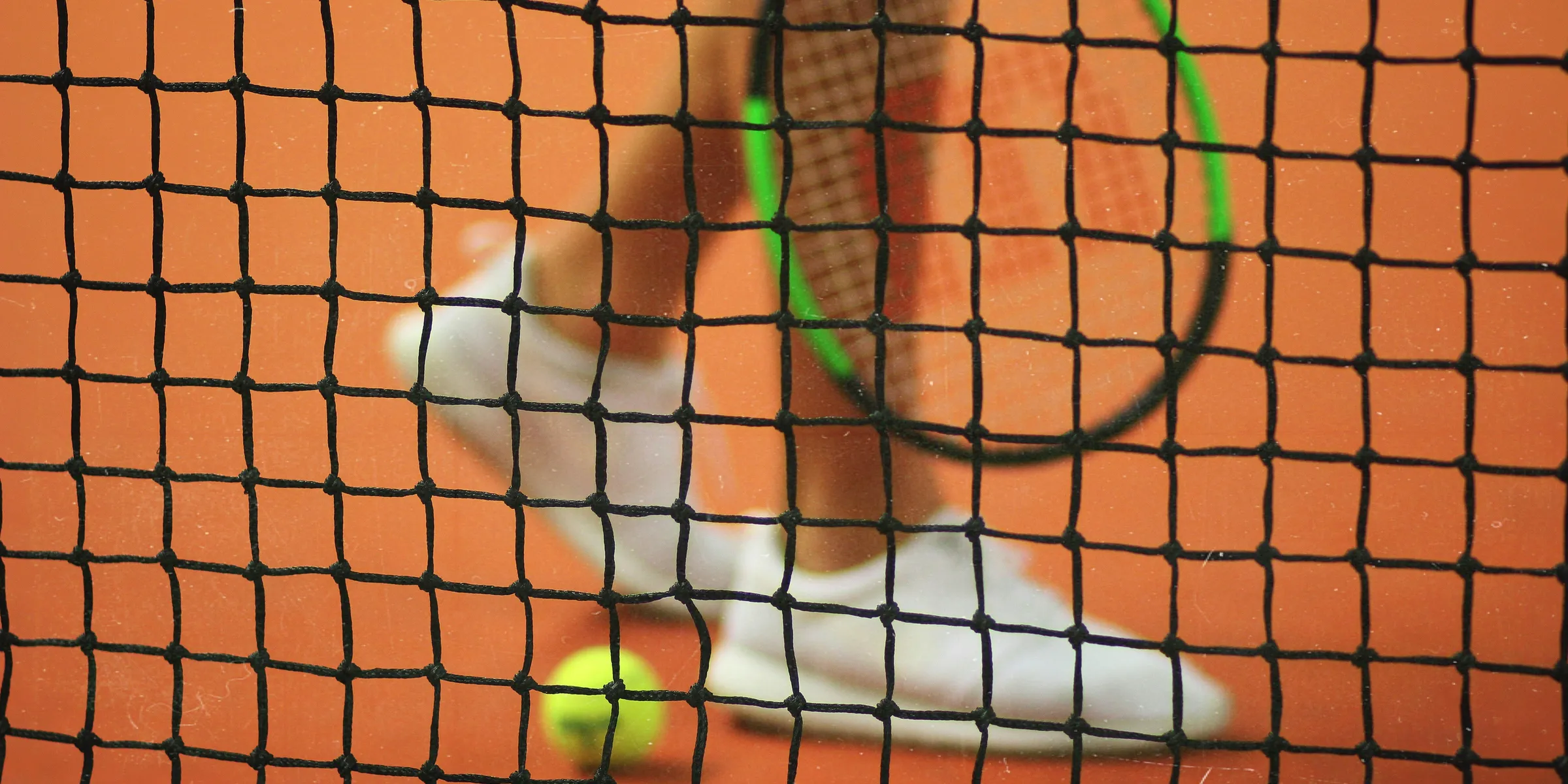 person wearing pair of white low-top sneakers while holding Wilson tennis racket