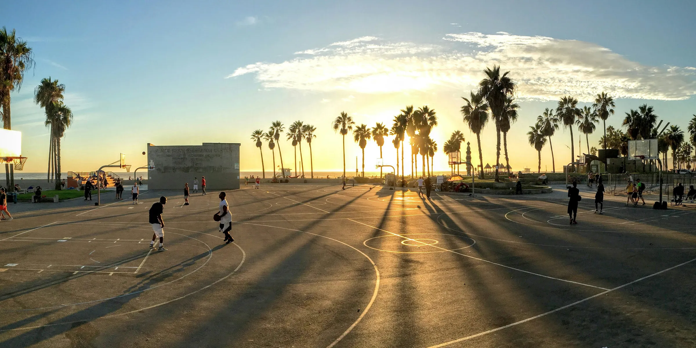 people playing basketball at court during sunset