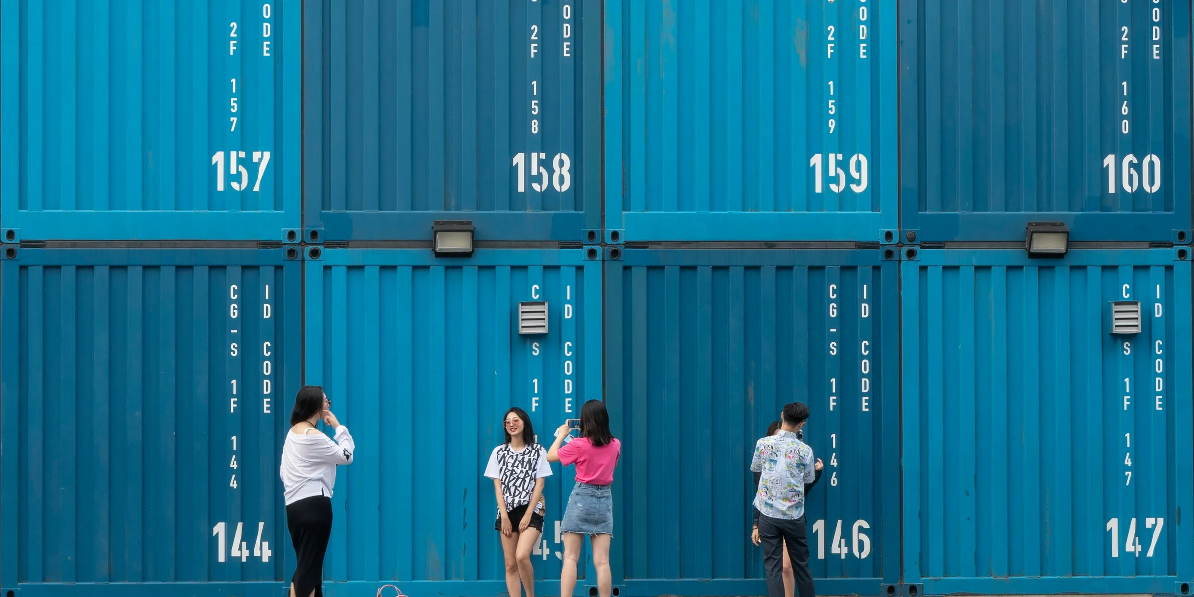 five women and man standing near shipping containers during daytime