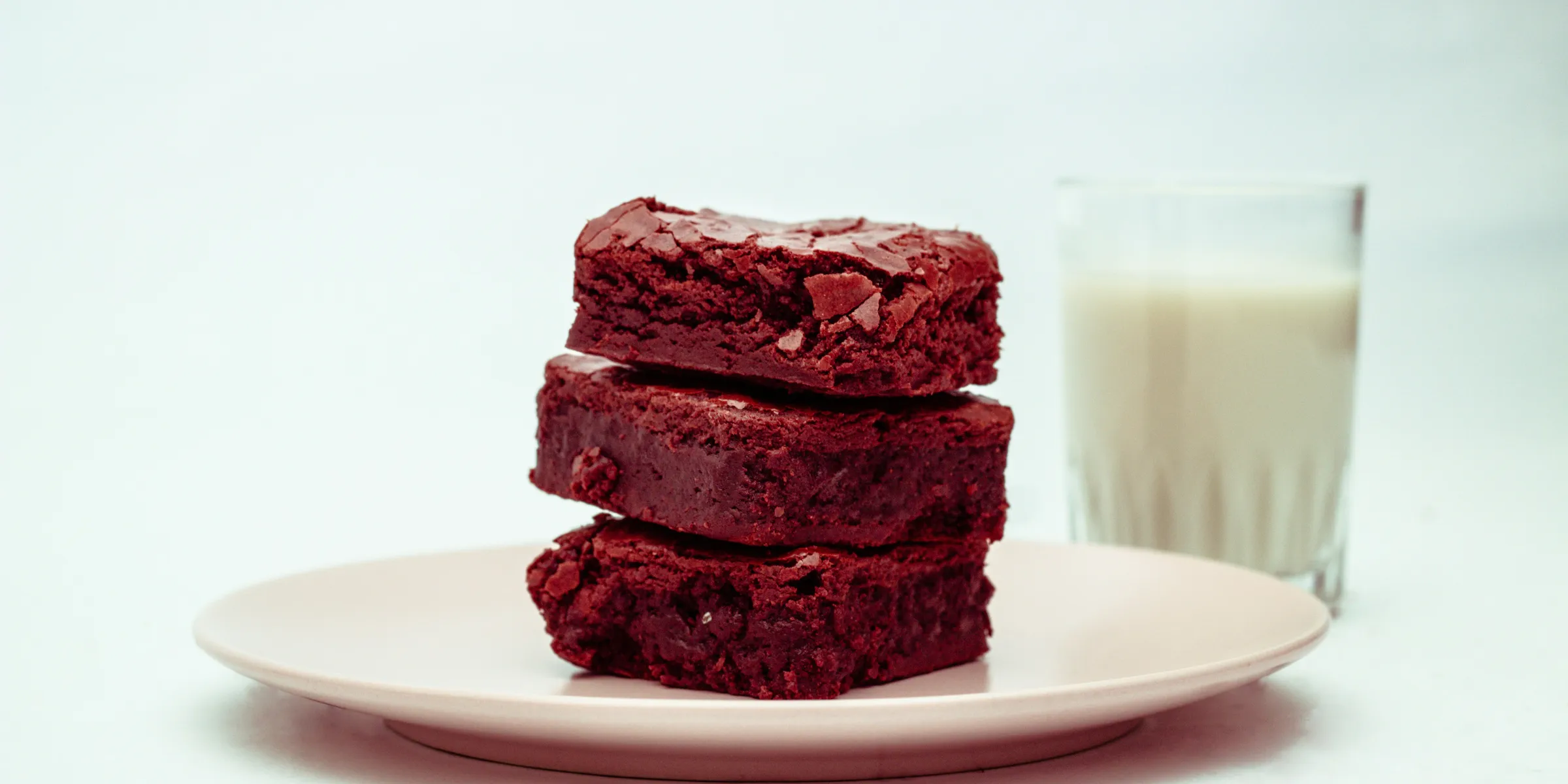 a plate of brownies next to a glass of milk