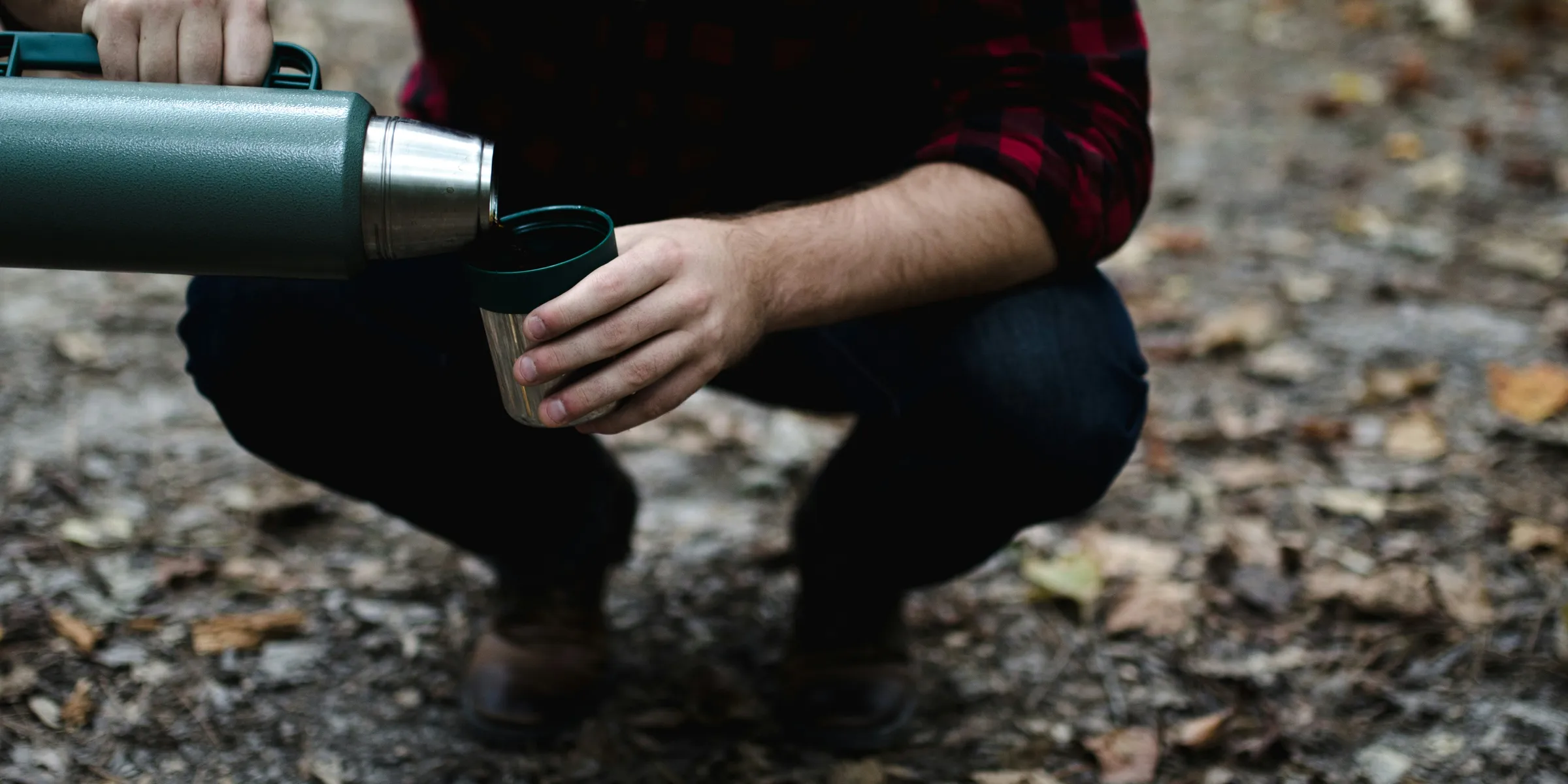 man bending his knees pouring thermal carafe in cup