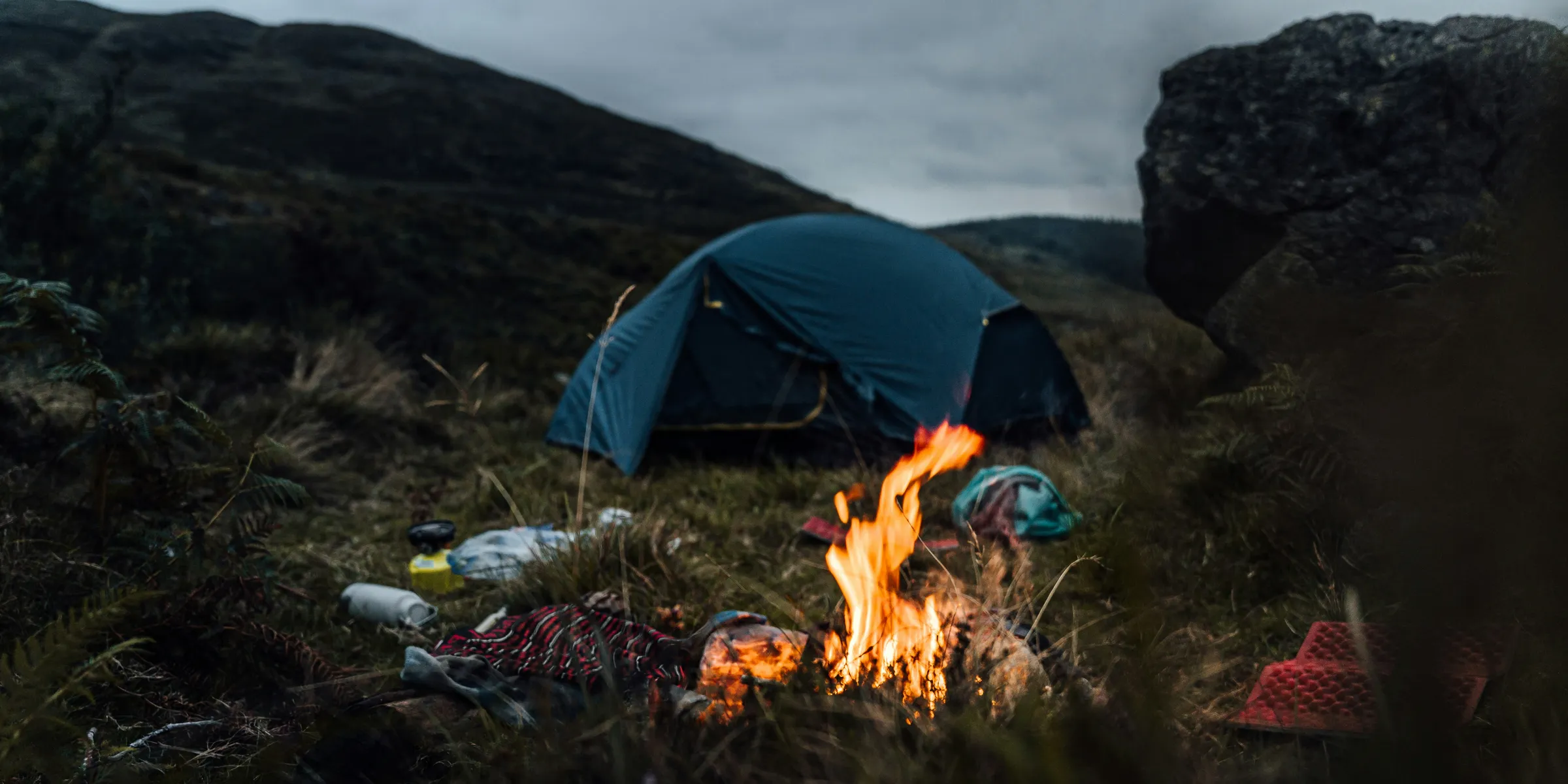 blue tent on green grass field near bonfire during night time