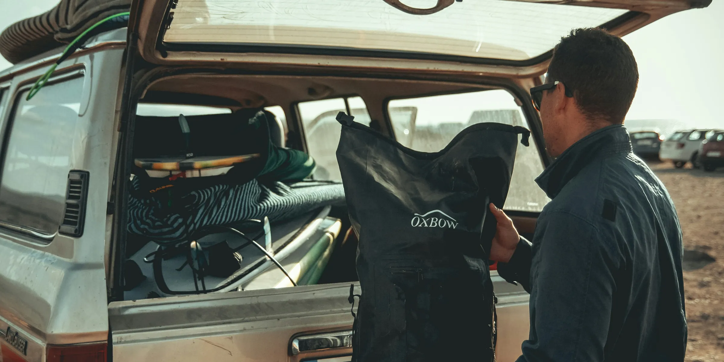 man loading black bag in back of suv