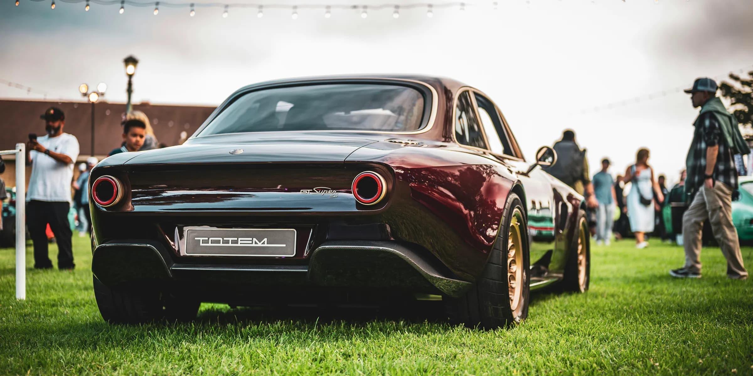 Vintage car parked on grassy field with people