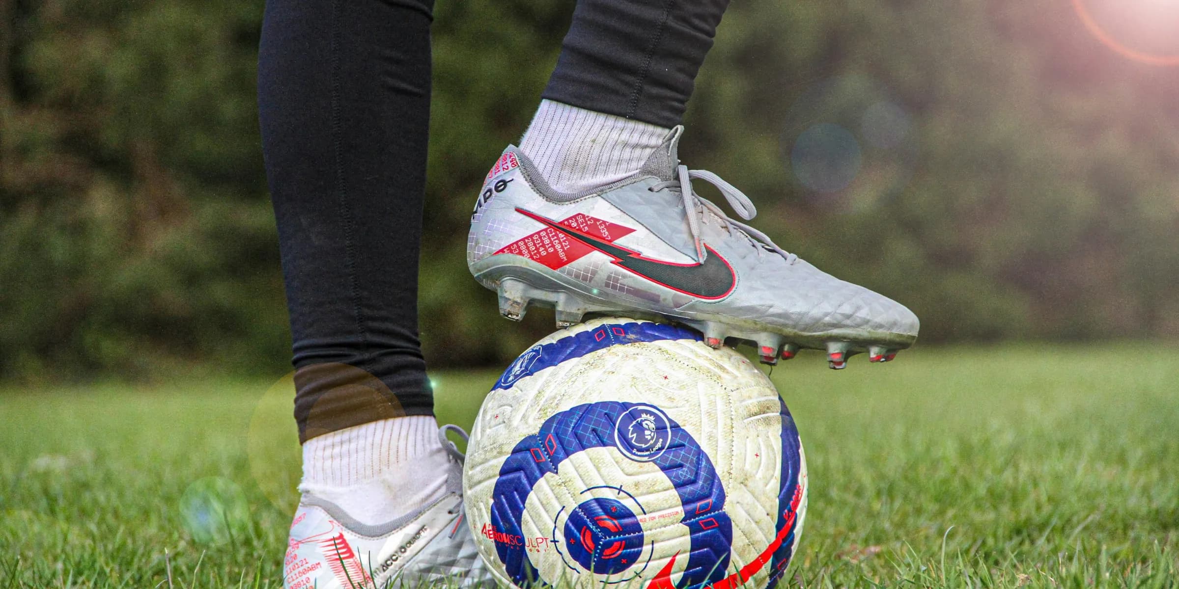 person in black pants wearing white and red nike soccer cleats