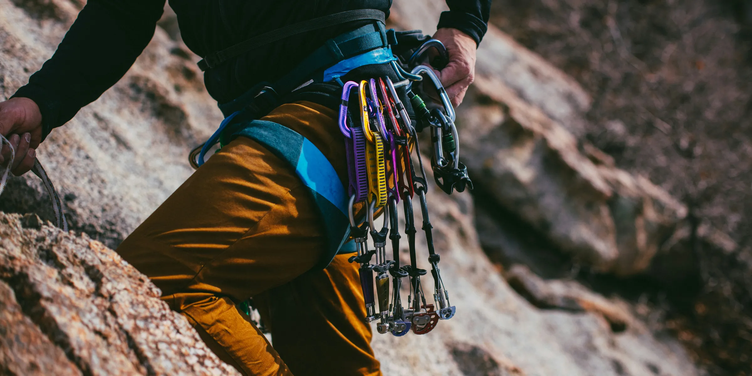 person in black jacket and brown pants with hiking backpack climbing mountain during daytime