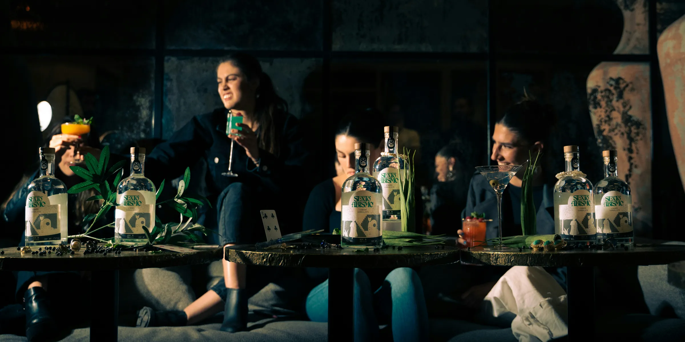 a group of people sitting at a table with bottles of alcohol