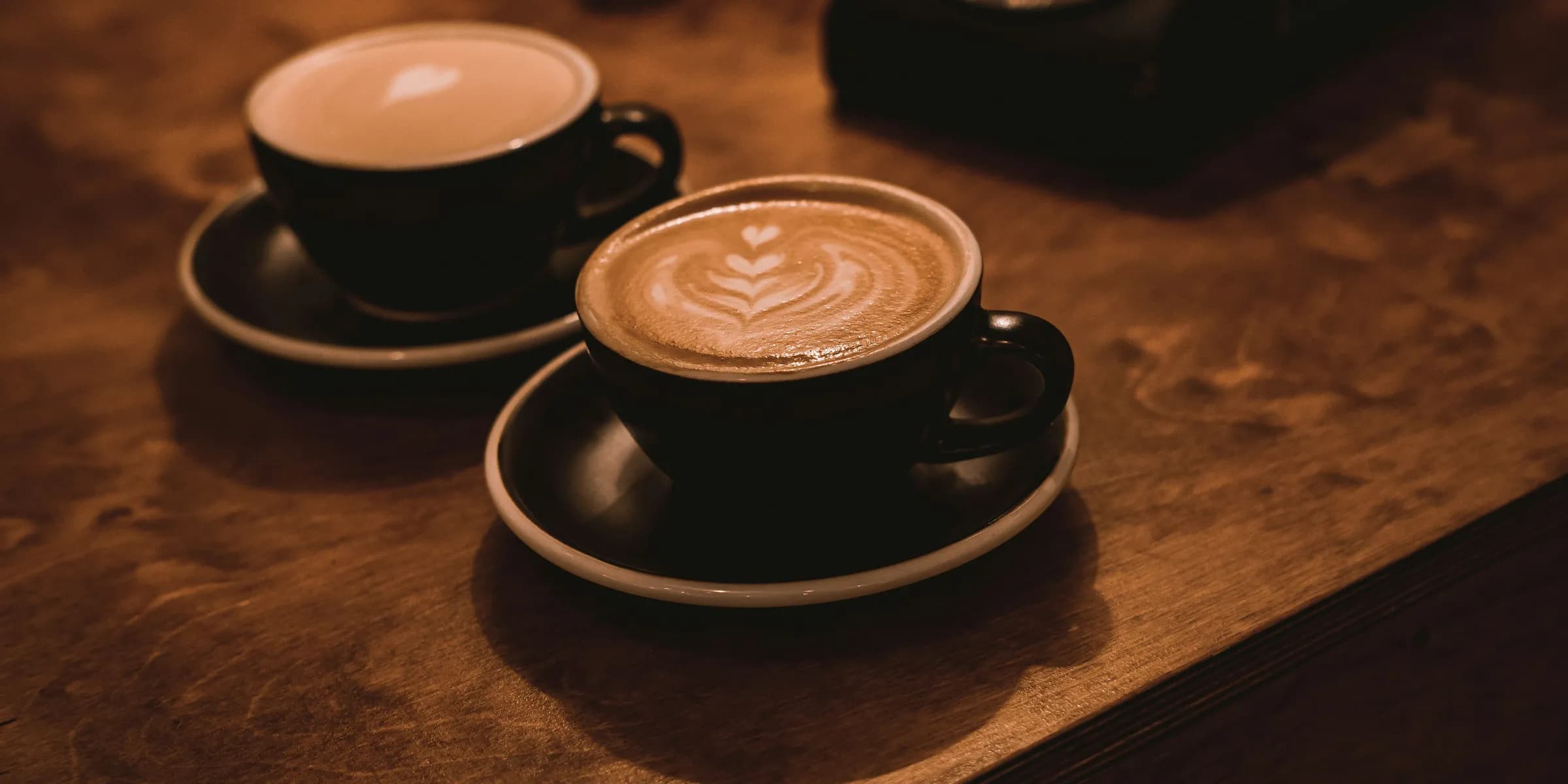 two cups of coffee sit on a wooden table