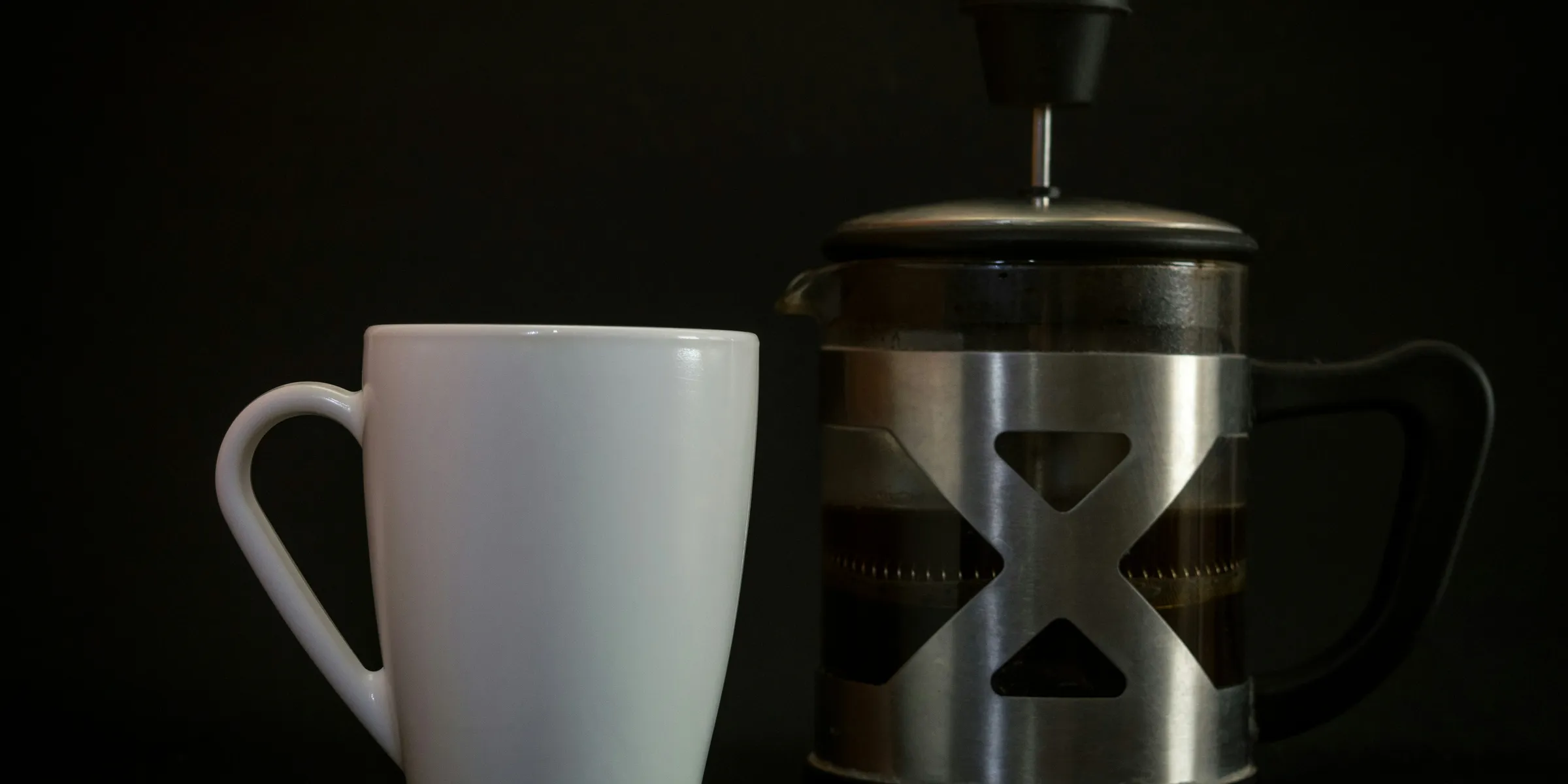 gray steel French press beside white ceramic mug