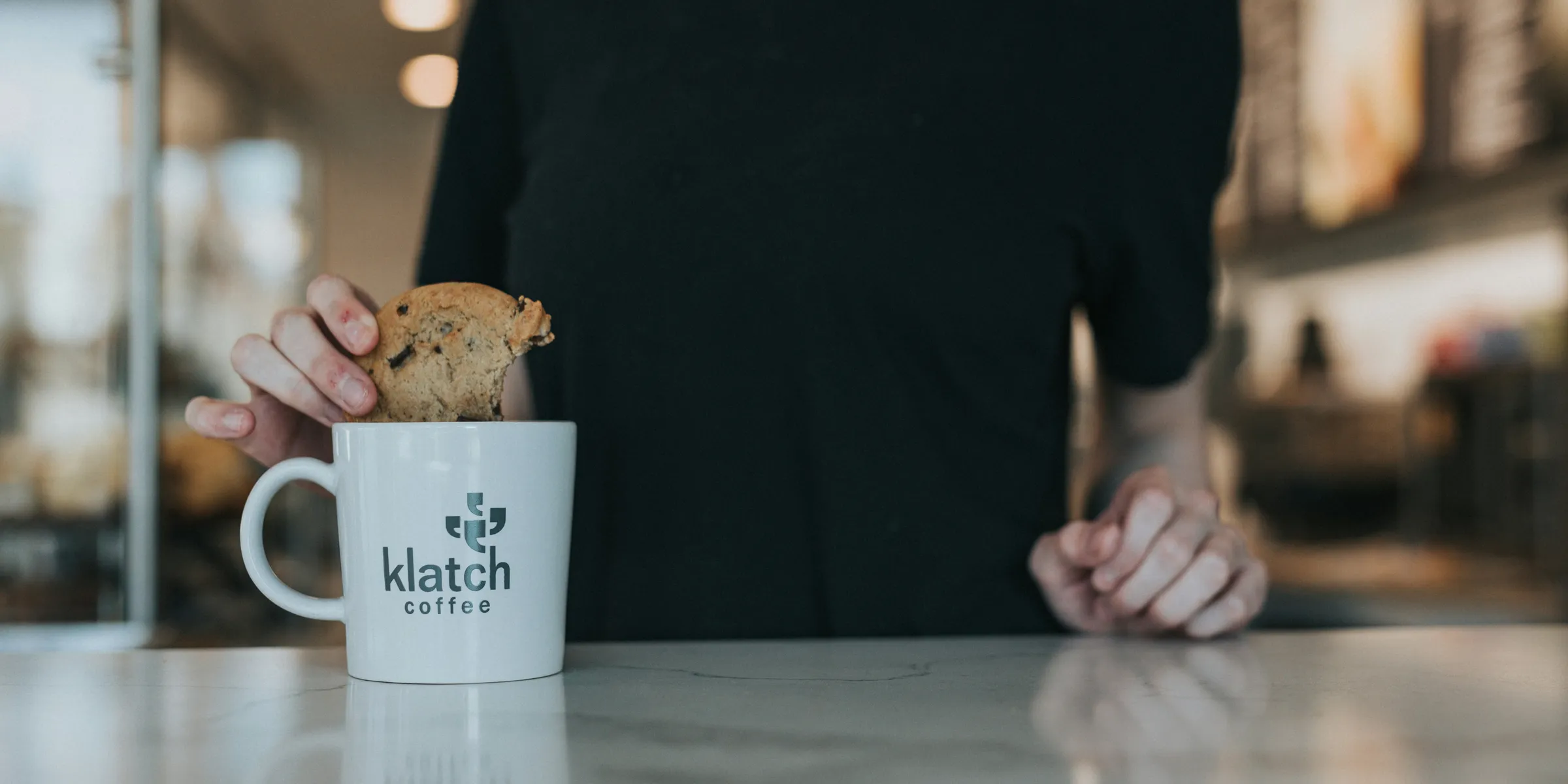 person in black crew neck t-shirt holding white and brown ceramic mug