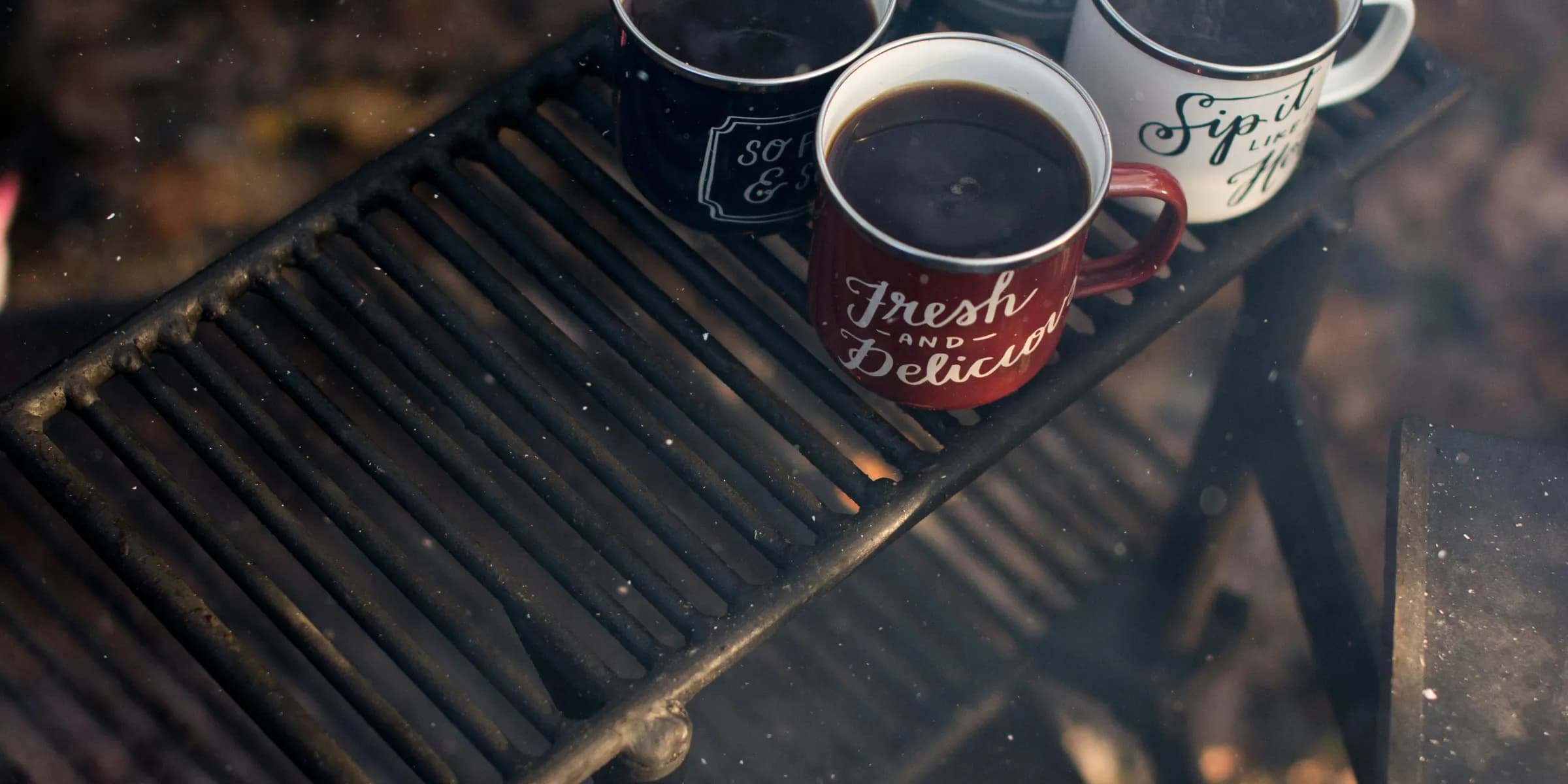 four assorted-color ceramic mugs on black grill frame