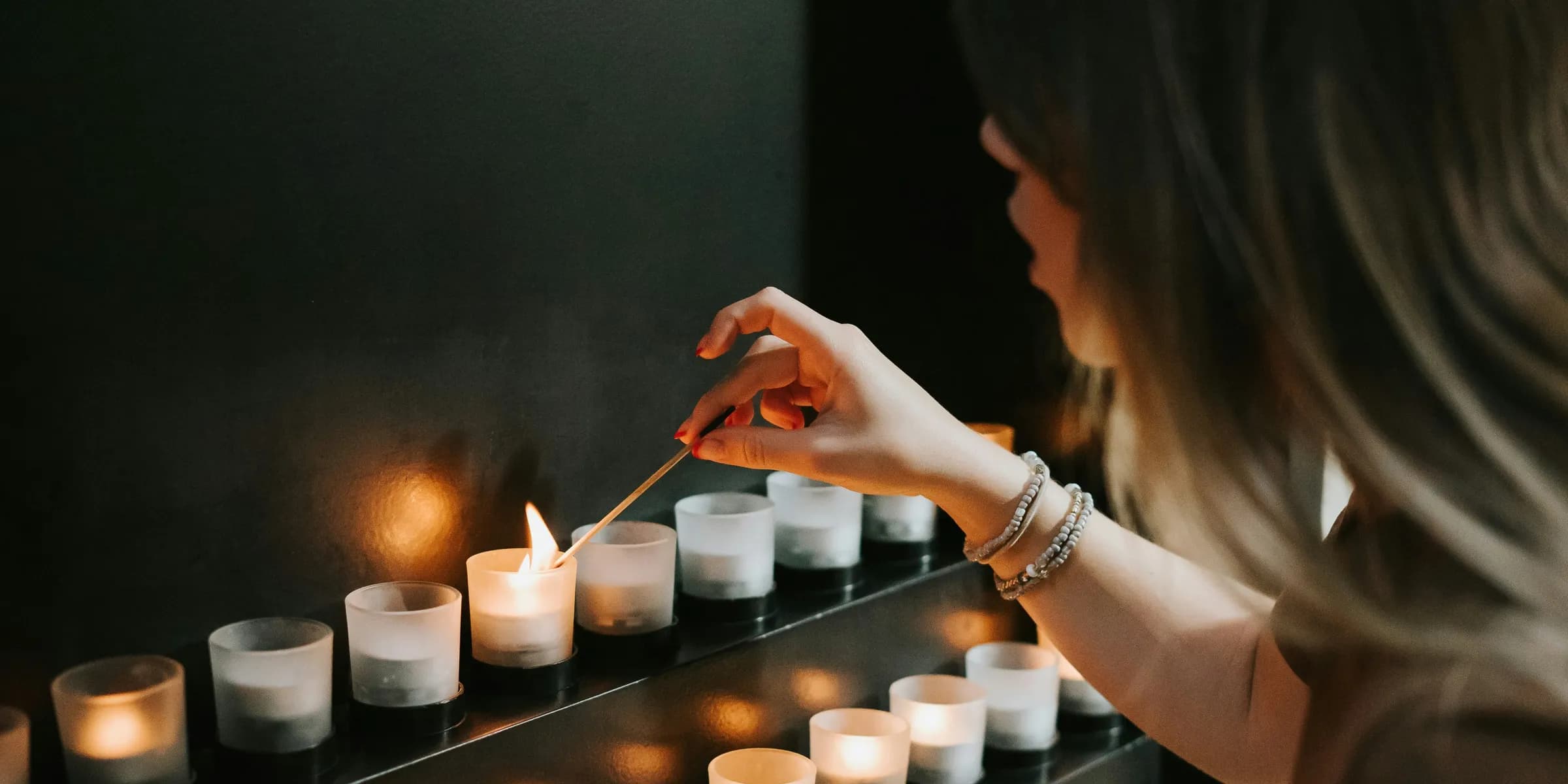 woman lighting a candle beside candles