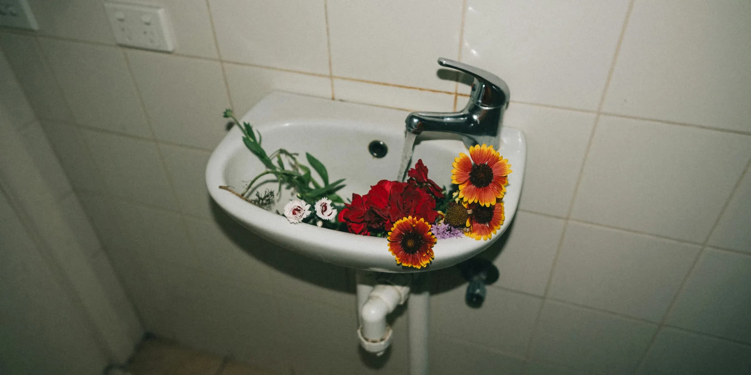 variety of flowers in white ceramic pedestal sink