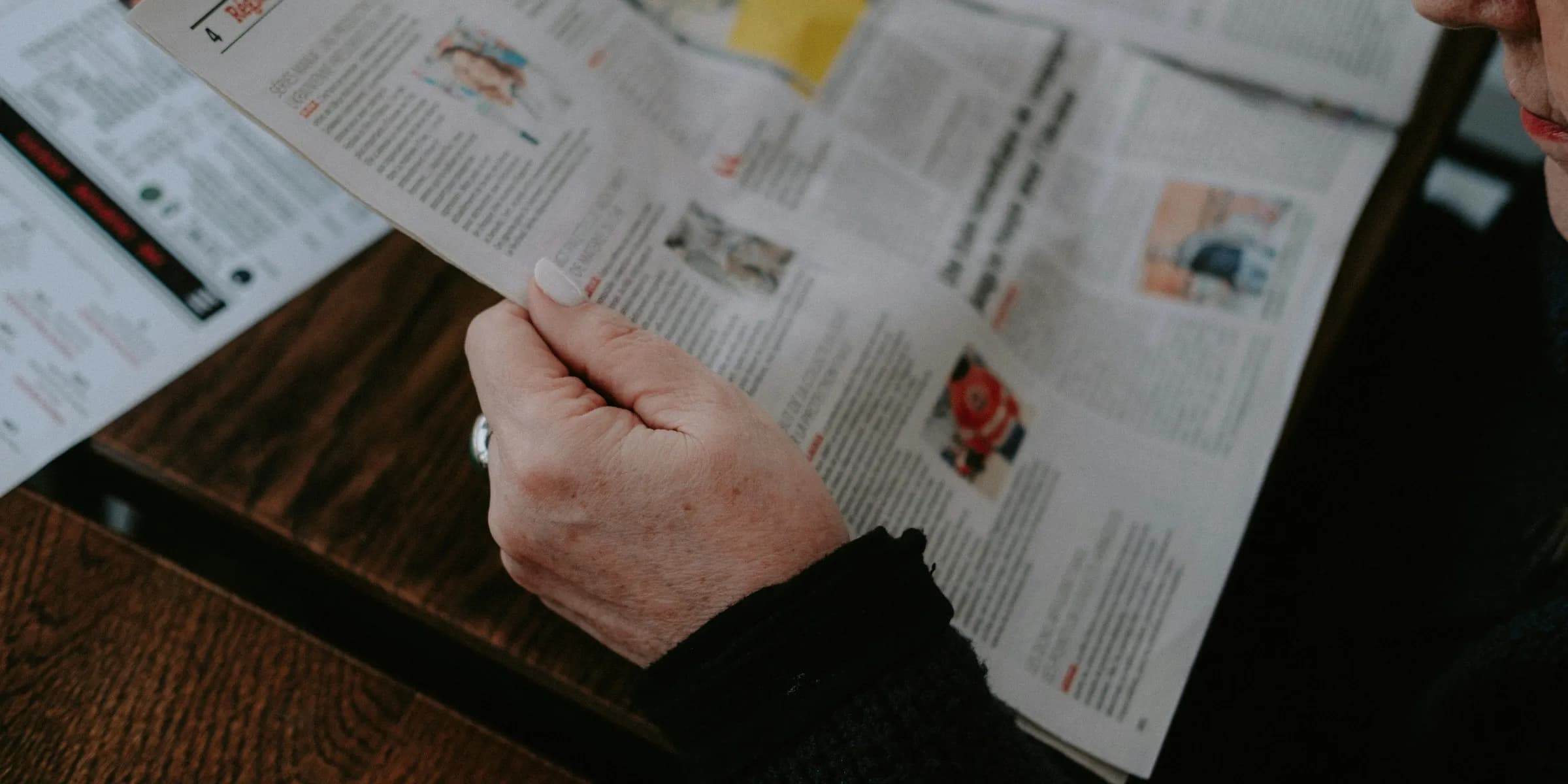 a person sitting at a table reading a newspaper