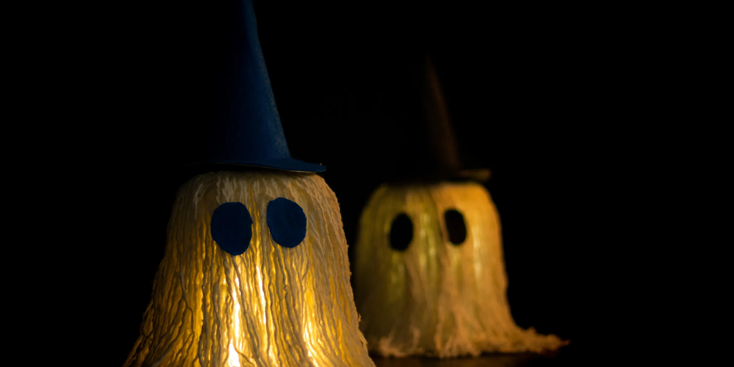 Two glowing ghost crafts wearing wizard hats at night