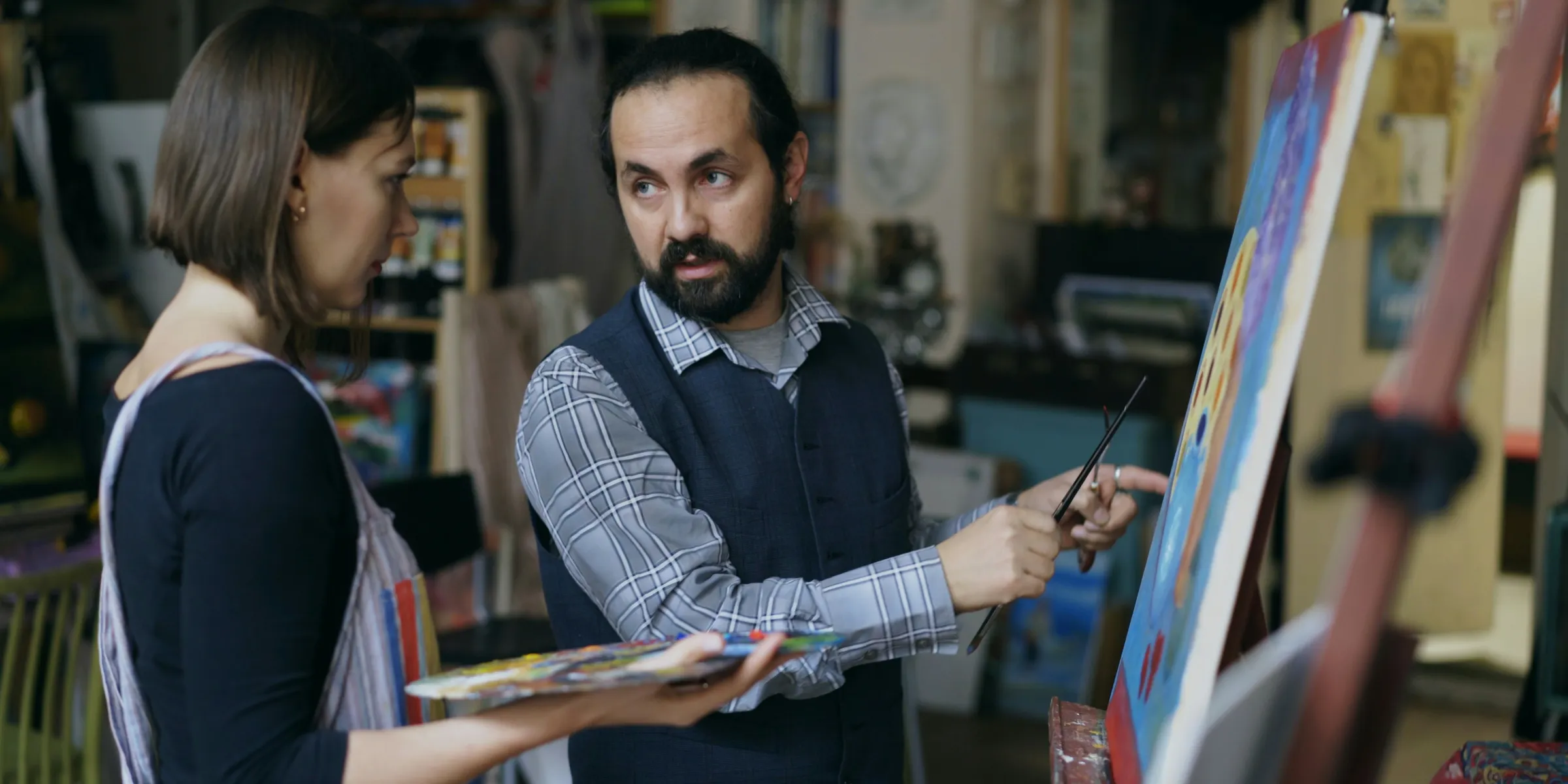 Artist teaching student painting in studio
