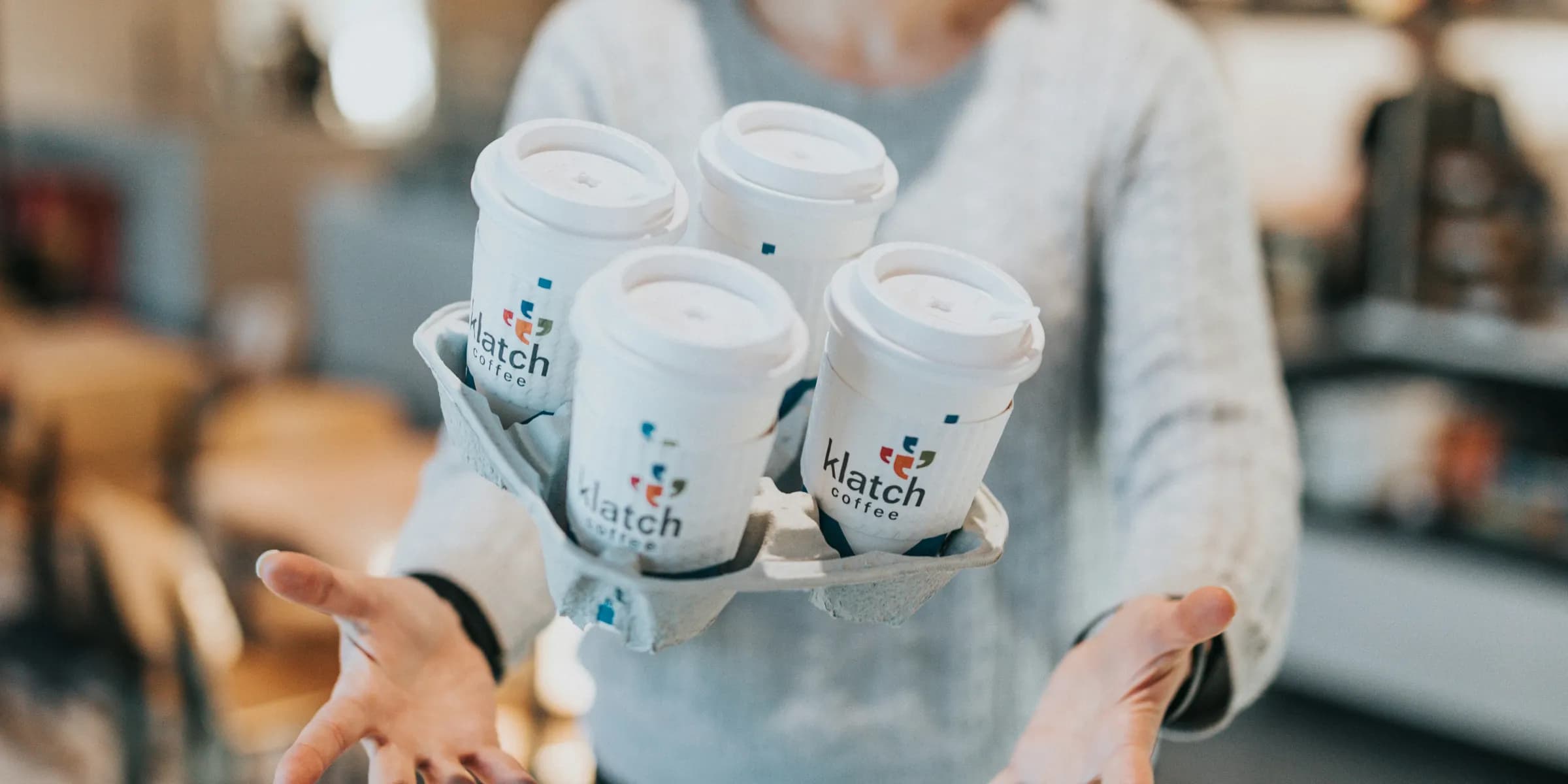 woman in gray sweater holding white ceramic mugs