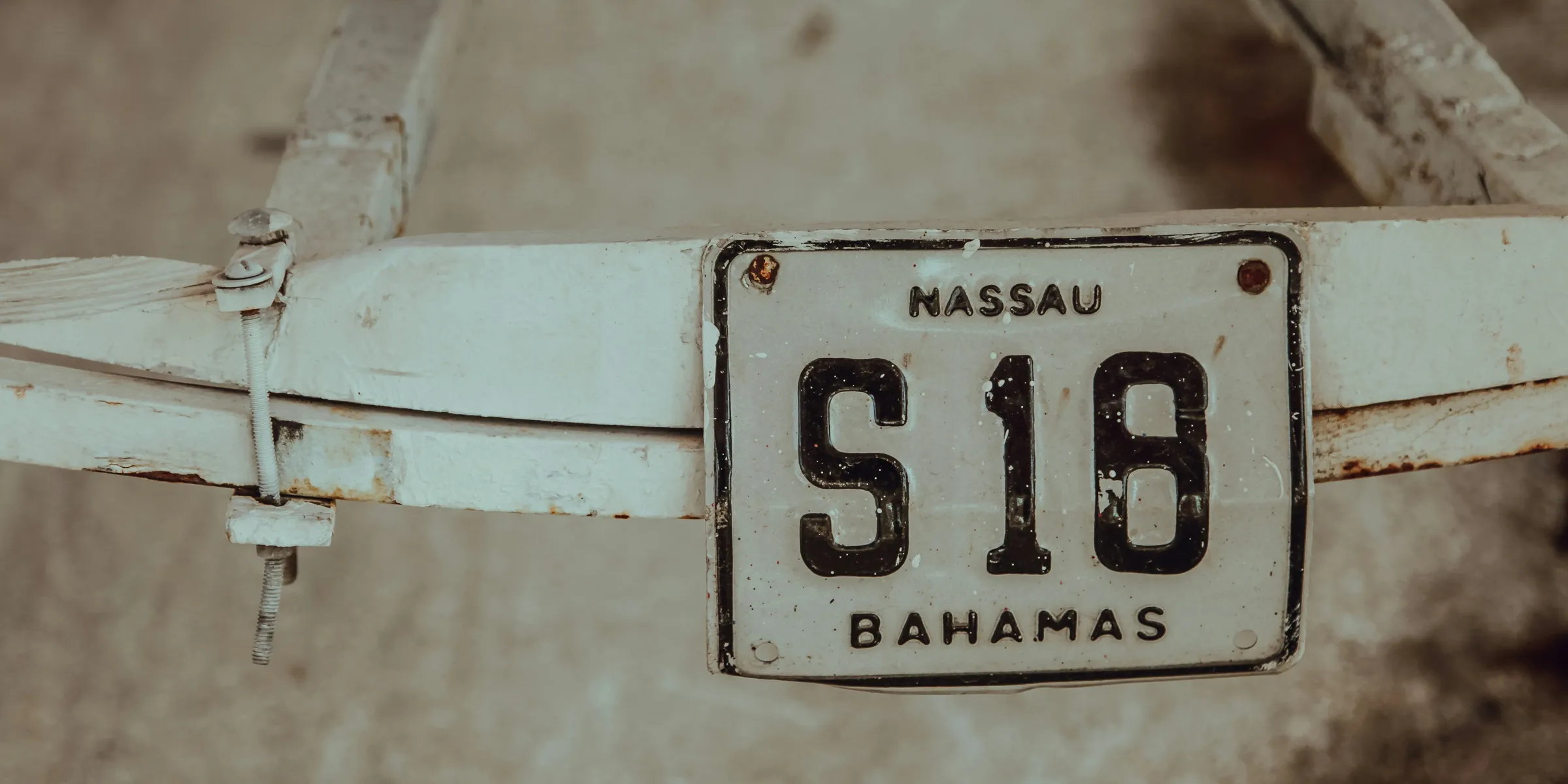 shallow focus photography of white Massau S18 Bahamas license plate mounted on white steel frame