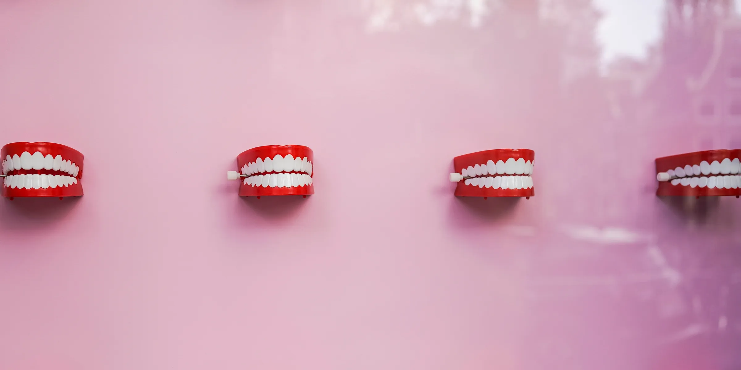 a pink wall with white teeth and braces on it