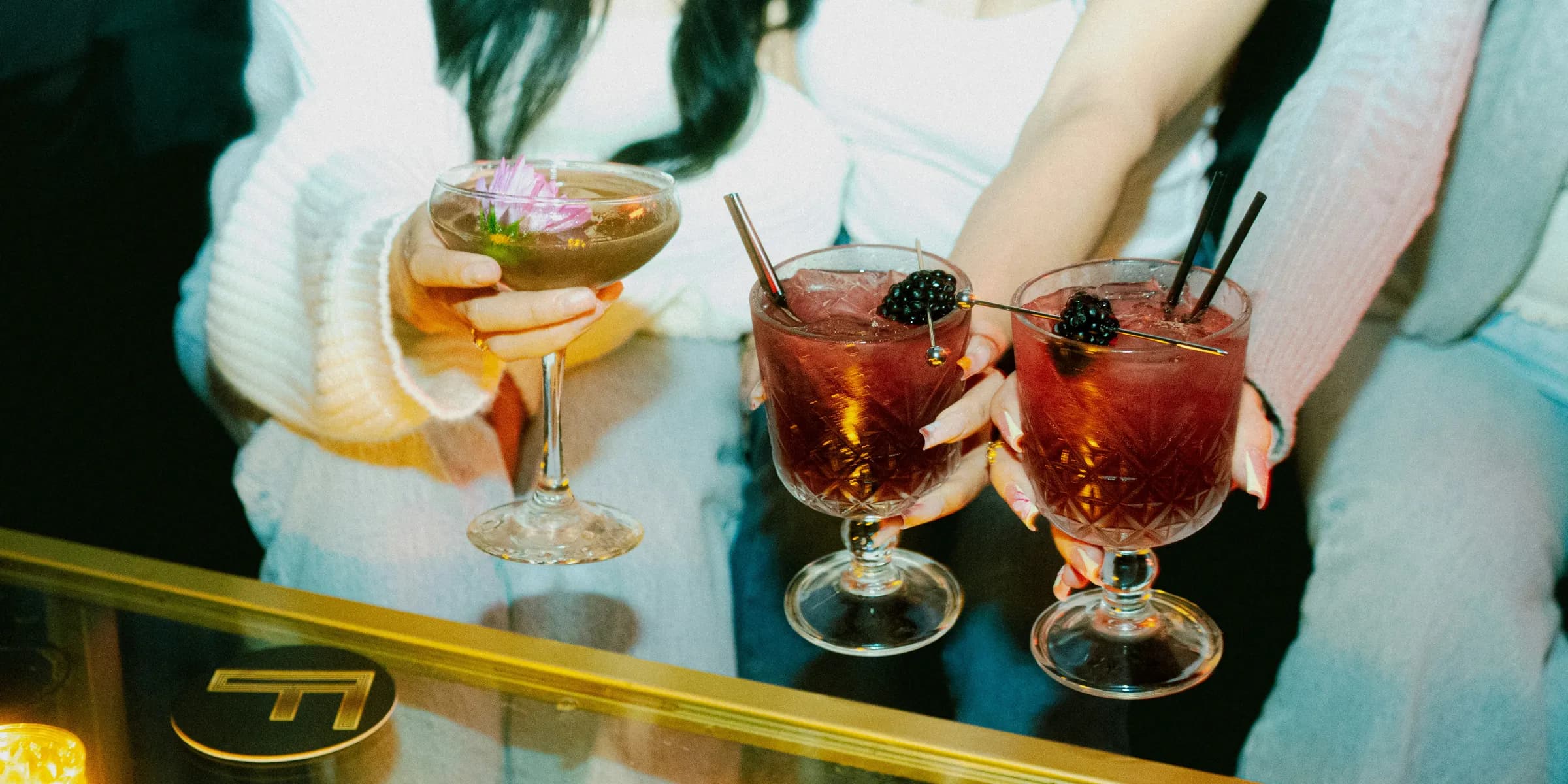 People enjoy cocktails at a dimly lit bar.