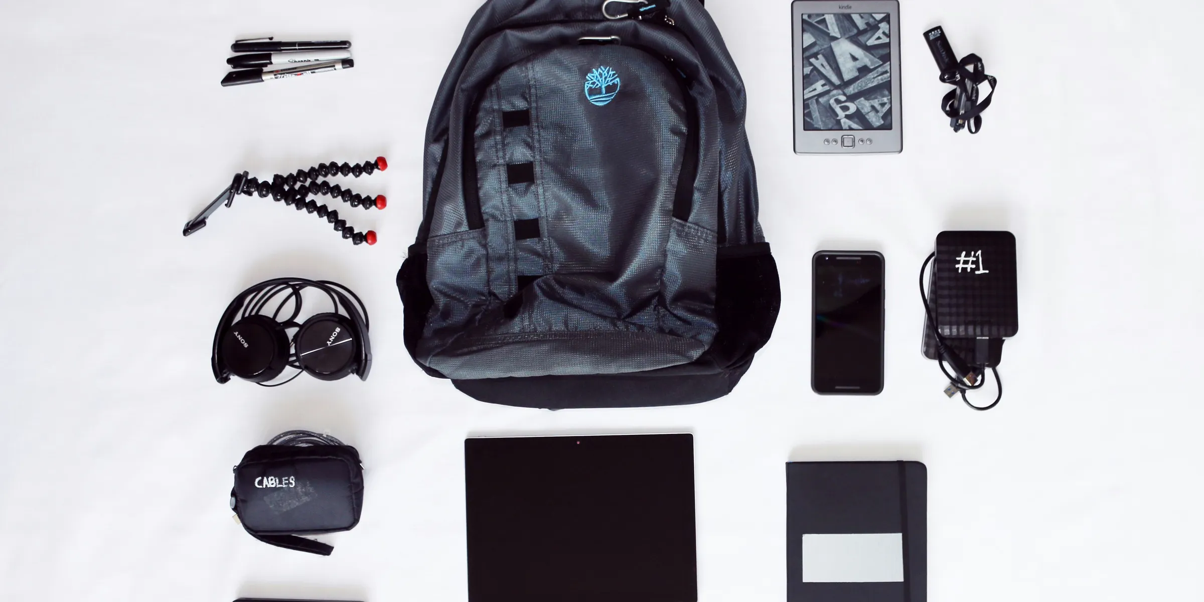 flat lay photography of backpack, laptop computer, headphones, smartphone, and octopus tripod