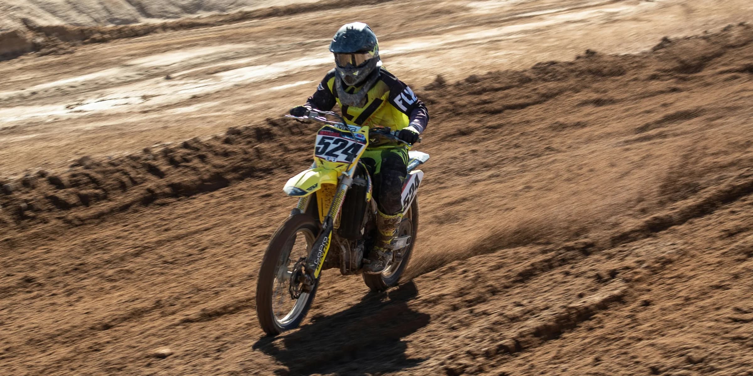man riding motocross dirt bike on brown sand during daytime