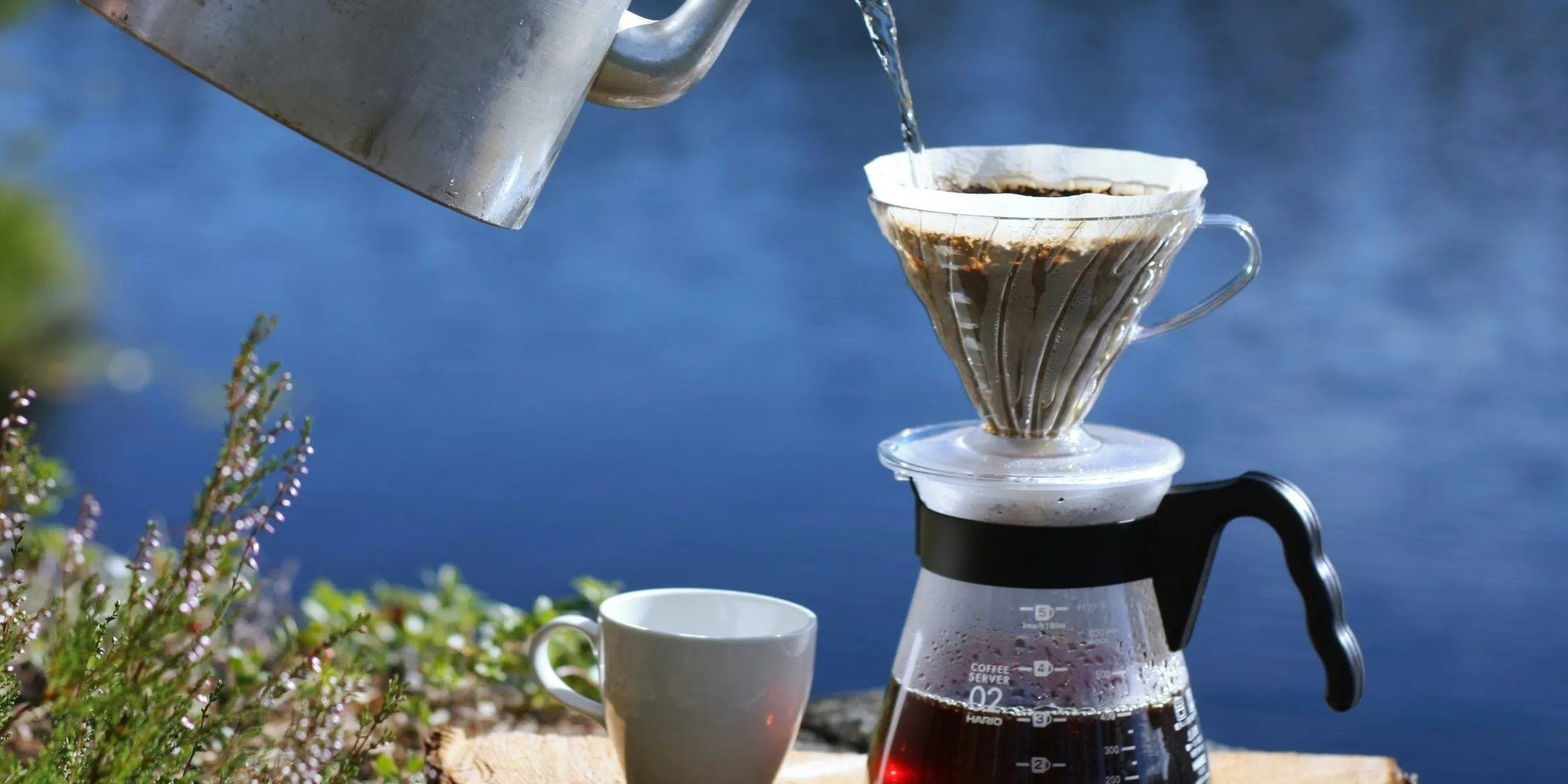 a coffee pot pouring water into a cup