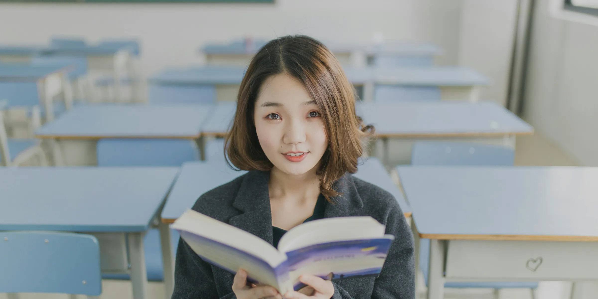 woman reading book sitting on chair in room