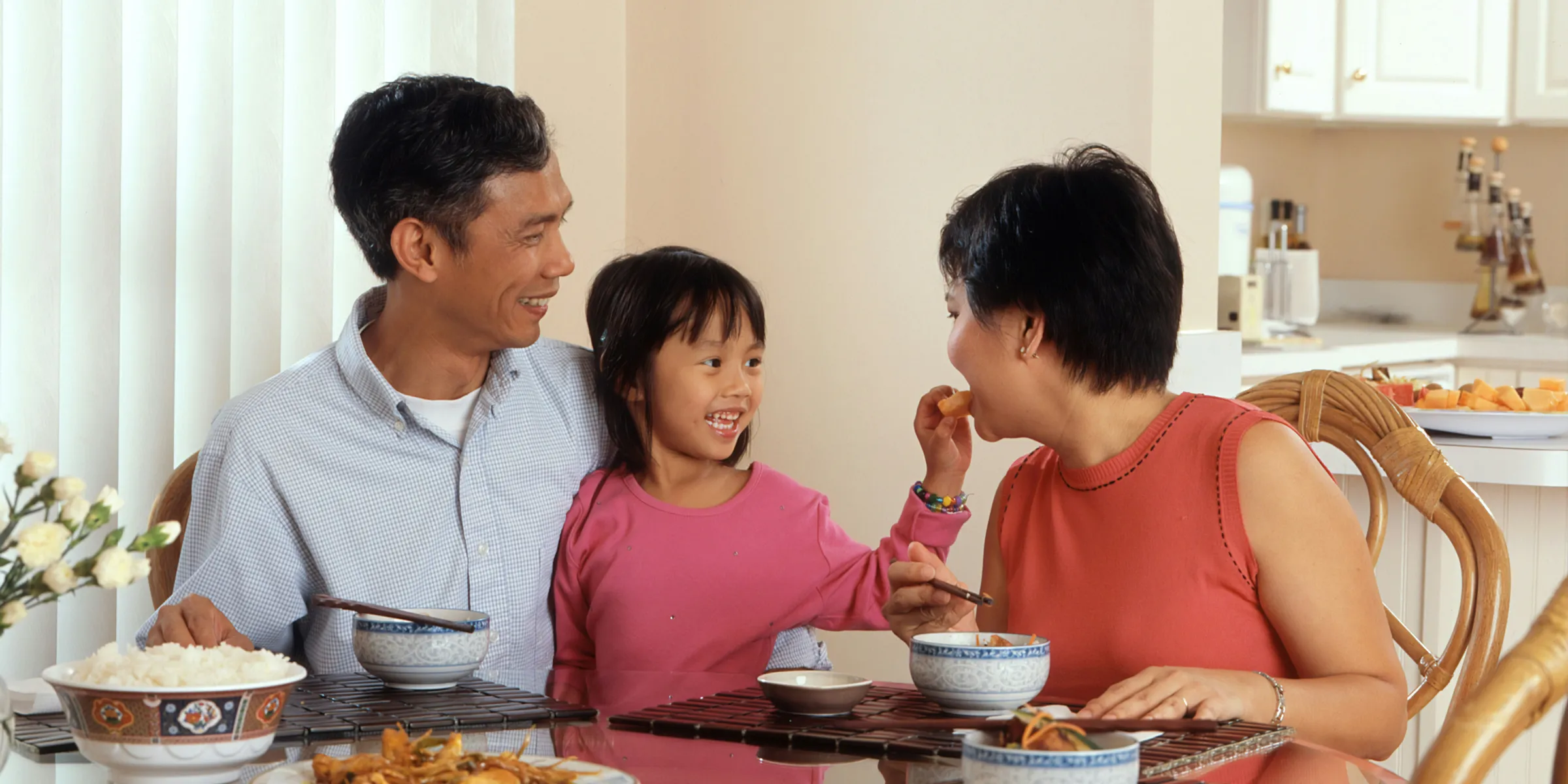 a man, woman and child sitting at a table eating food