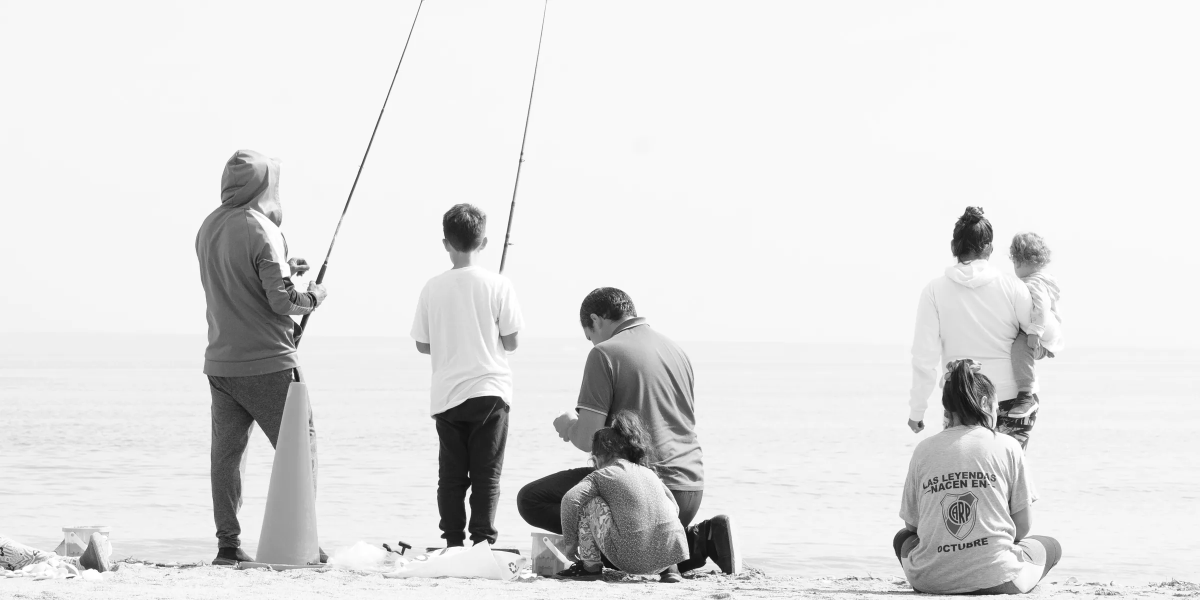 Family fishing together on a sandy beach.
