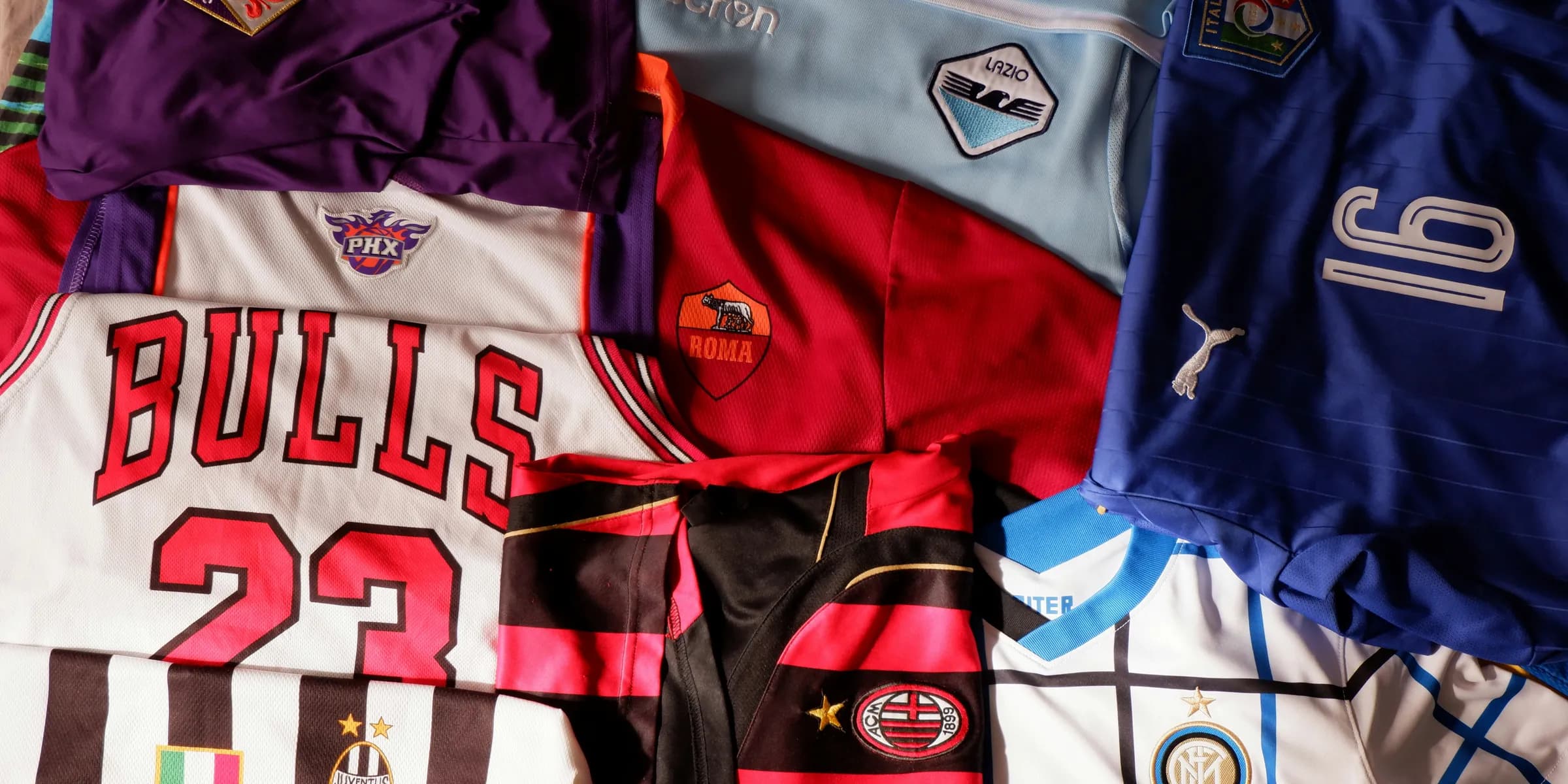 a pile of sports jerseys sitting on top of a bed