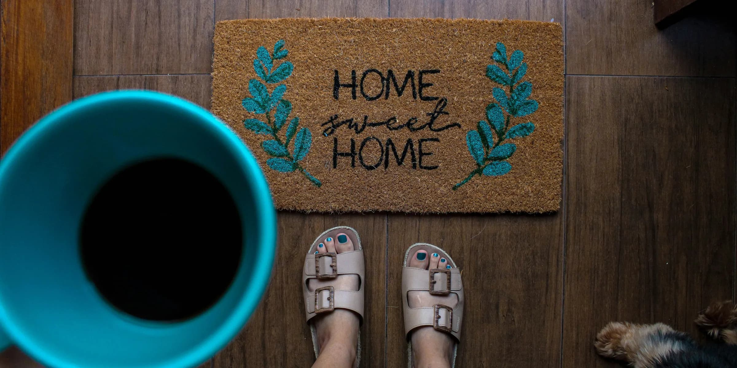 person in white leather sandals standing on brown wooden floor