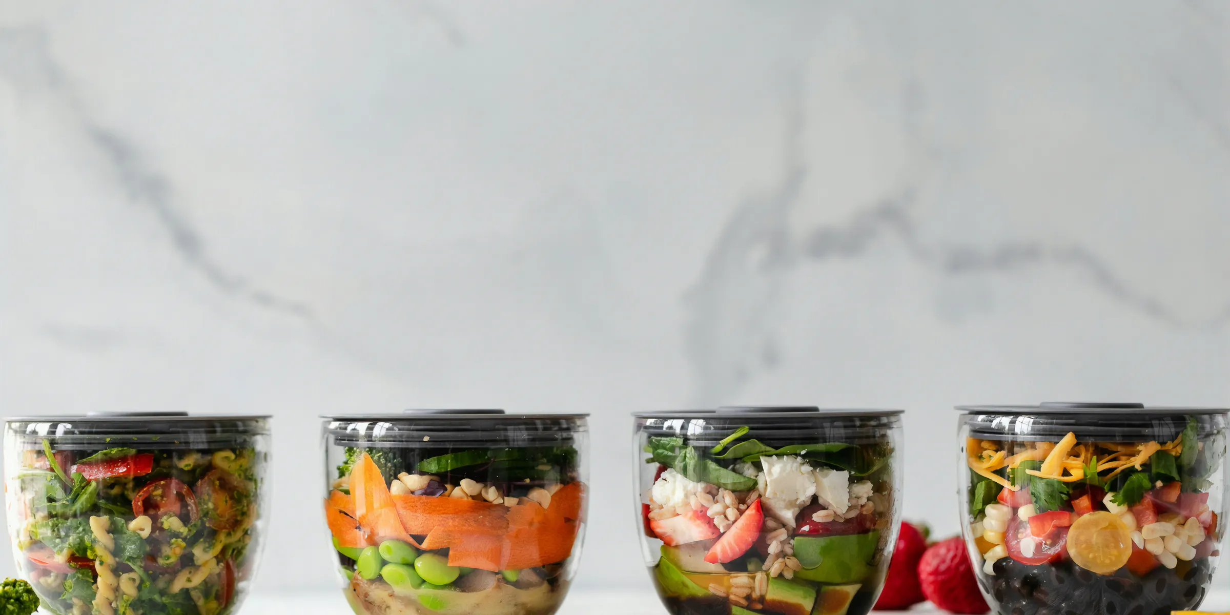 four clear plastic bowls with vegetables