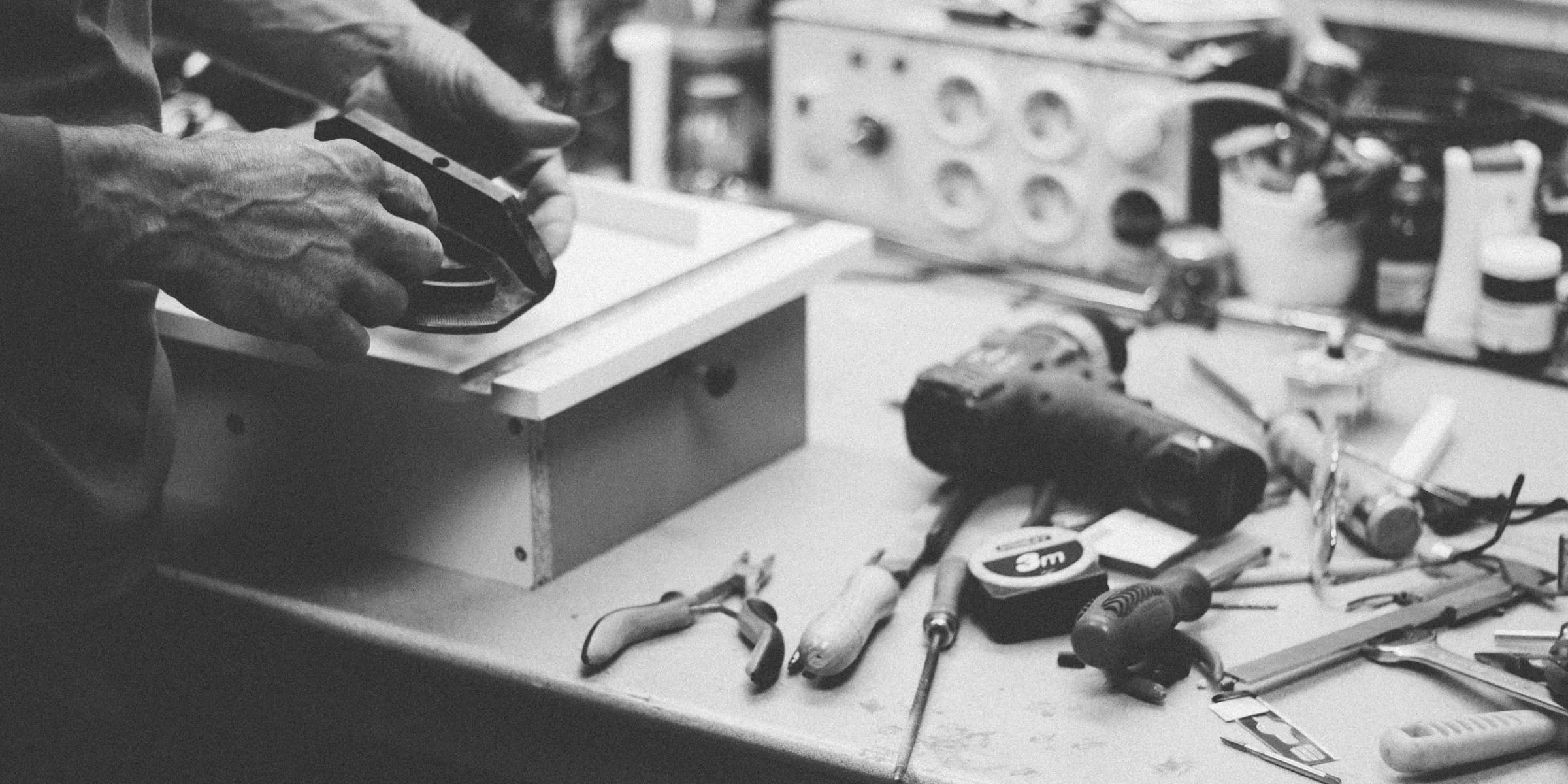 grayscale photo of person standing beside power tools on table